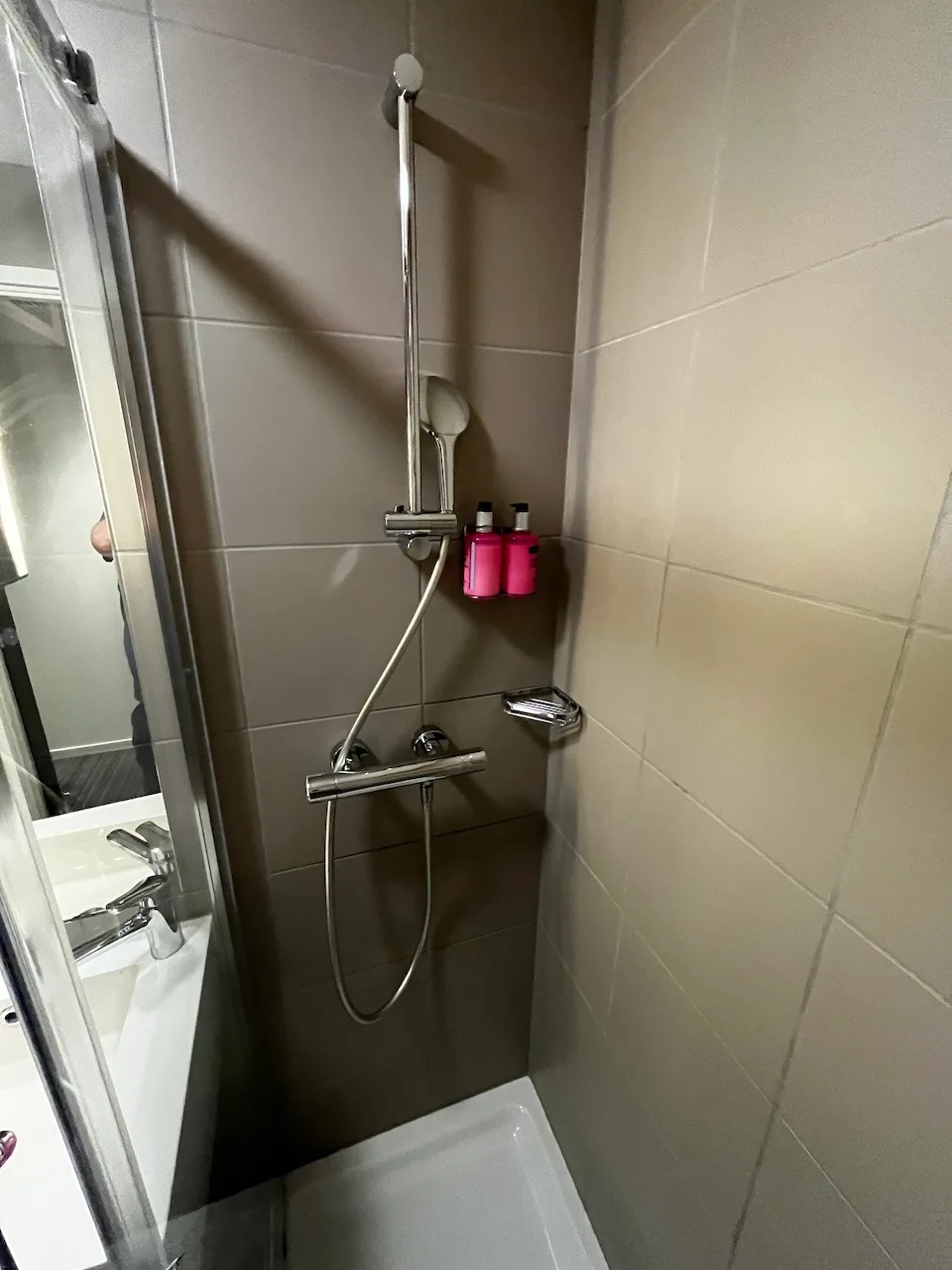 Duschbereich mit Regendusche und Kosmetikflaschen