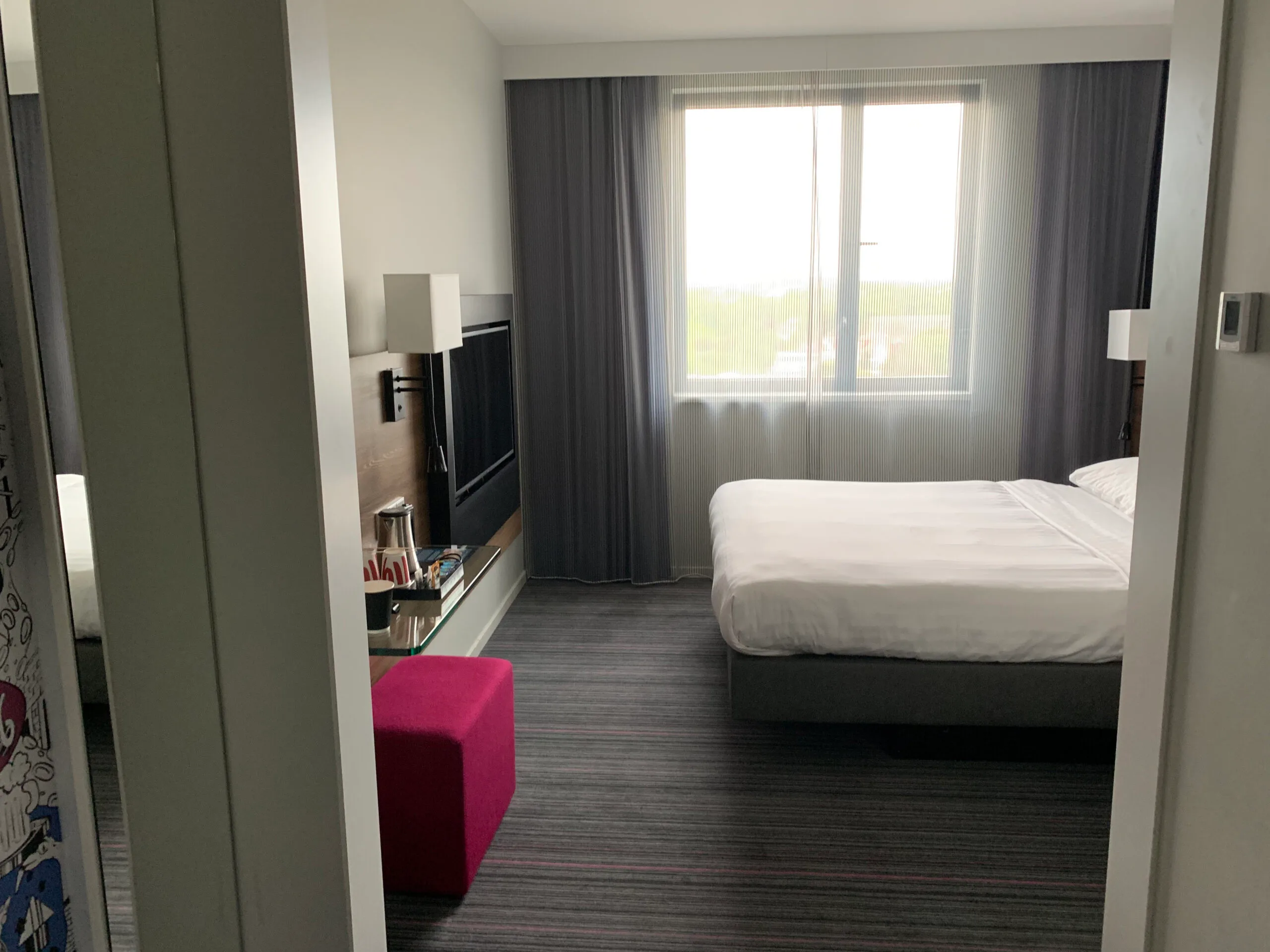 Hotelzimmer mit Doppelbett und grauem Vorhang