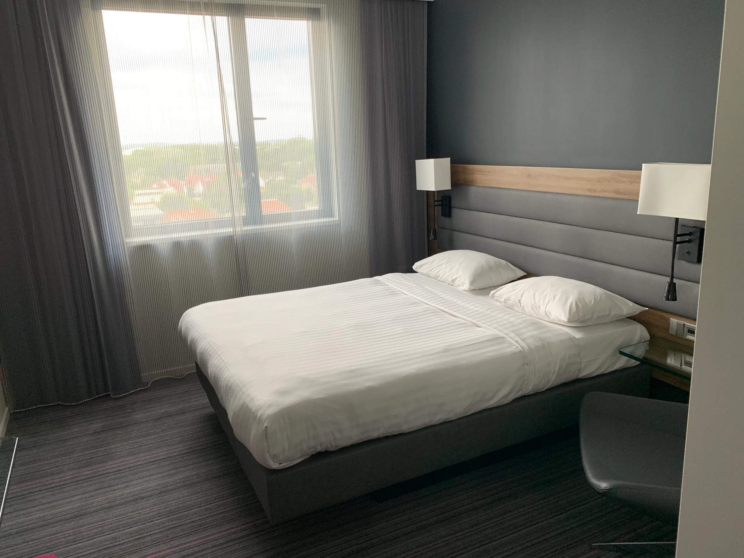 Hotelzimmer mit Doppelbett und grauem Vorhang