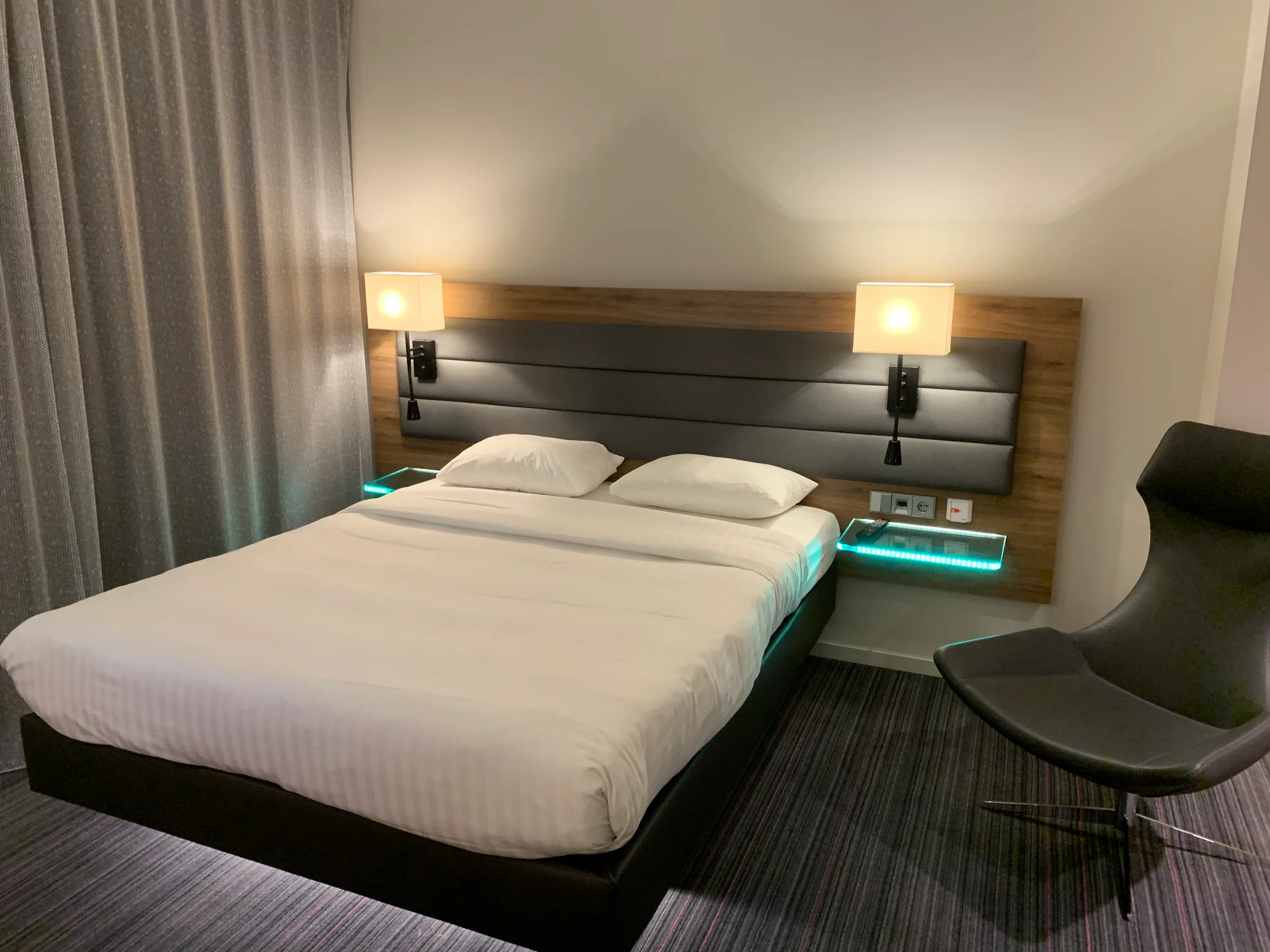 Doppelbett im Hotelzimmer mit Holzverkleidung und Nachttischen