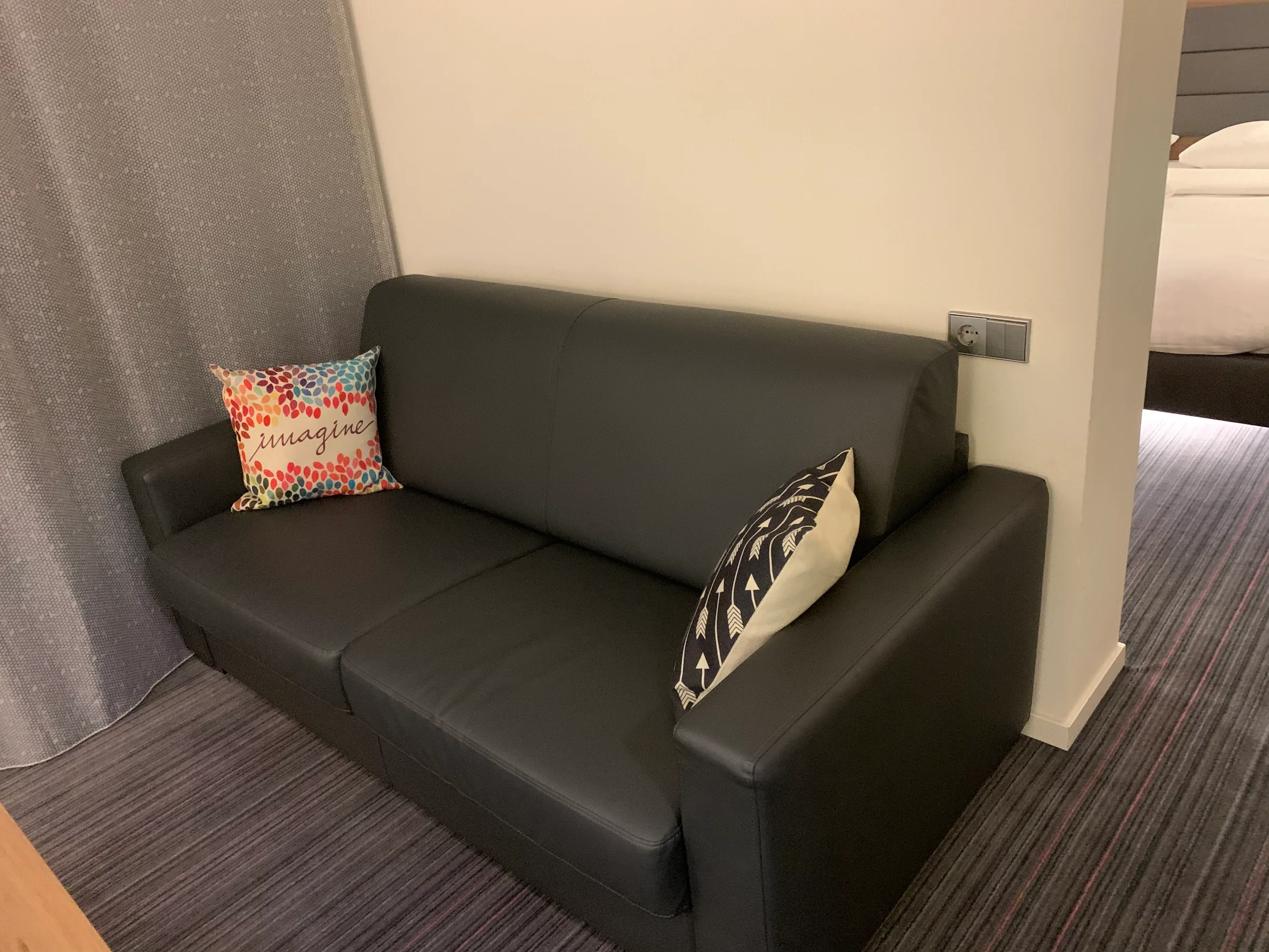 Schwarzes Sofa mit Kissen in Grau und buntem Muster