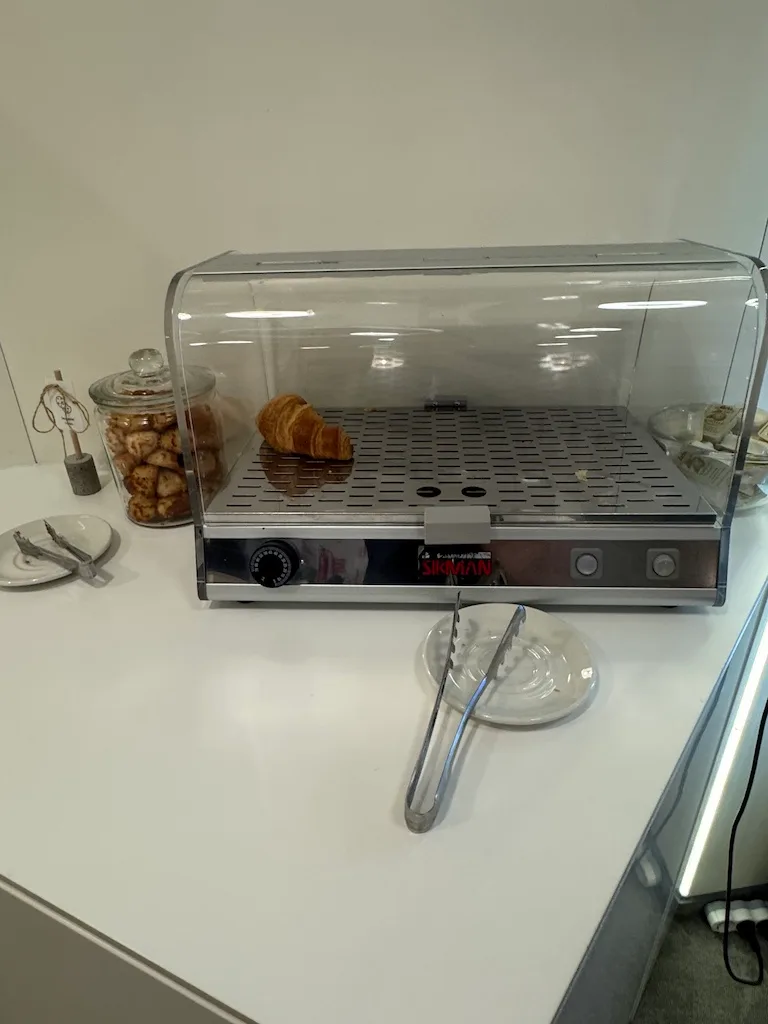 Heizkasten mit Croissant und Gabel auf Teller
