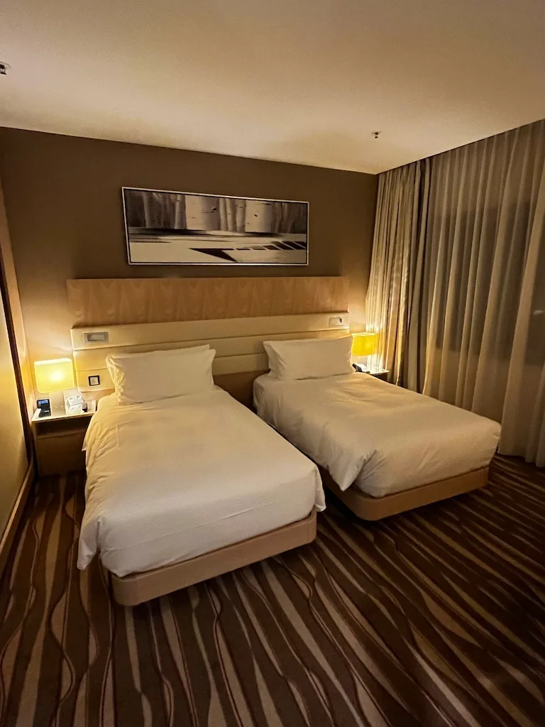 Hotelzimmer mit zwei Einzelbetten und grauem Tagesdecken
