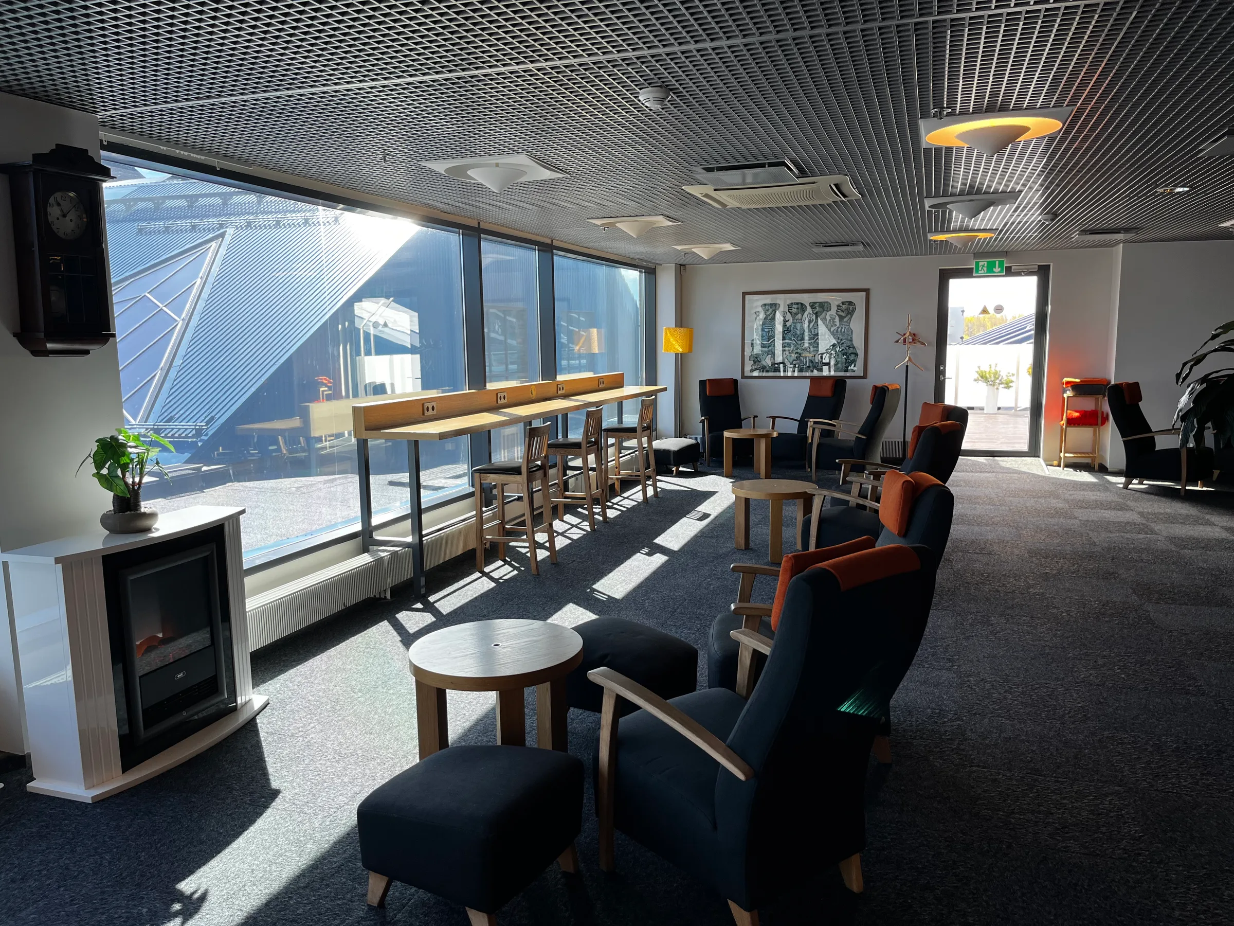 Lounge mit Sesseln und Barhockern vor großem Fenster