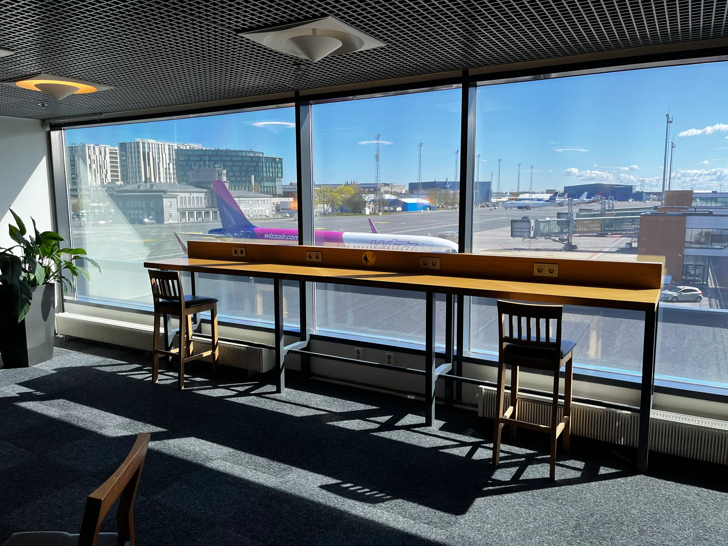 Lounge mit Tischen und Stühlen vor Flugzeugfenster