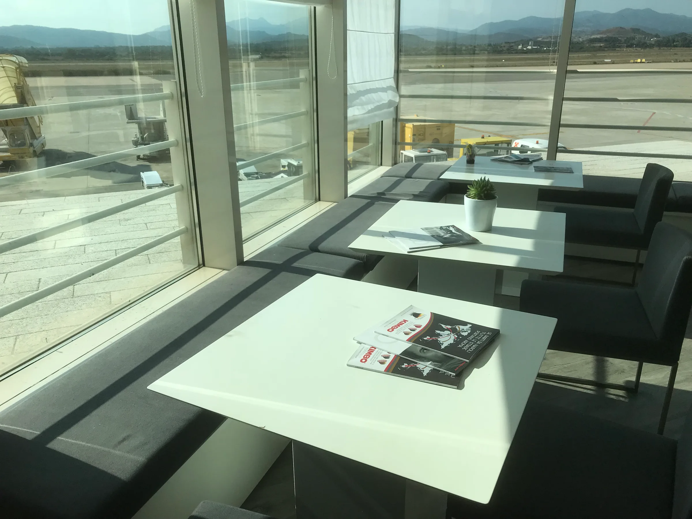 Lounge-Tische mit Zeitungen und Pflanze am Fenster im Flughafen