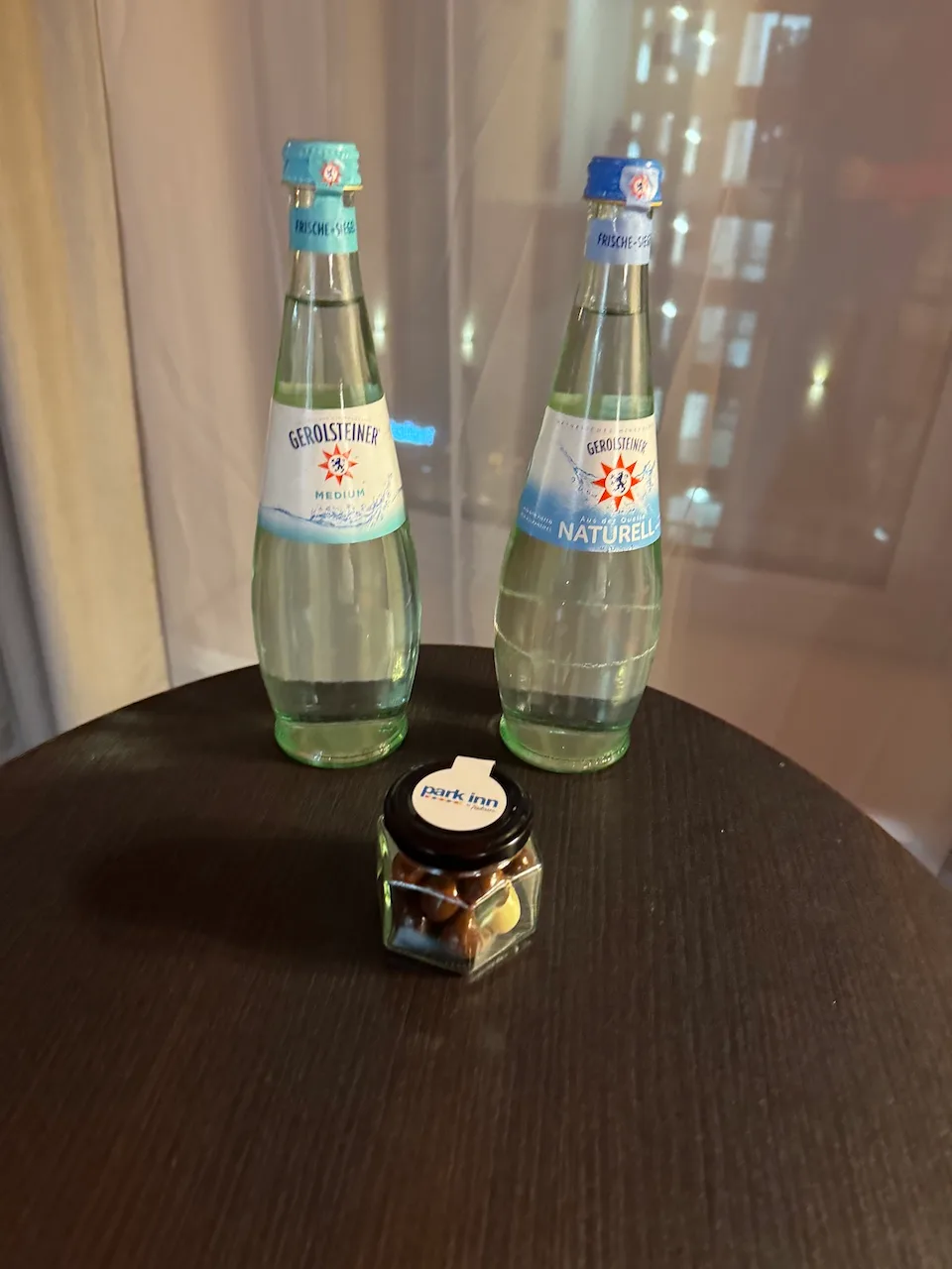 Zwei Flaschen Mineralwasser und eine kleine Schachtel Snacks auf einem Holztisch