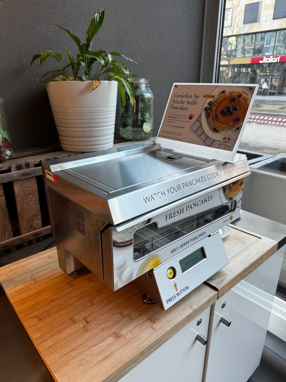 Selberbedienender Pancake-Maker mit Bildschirm und Werbung für frische Pfannkuchen