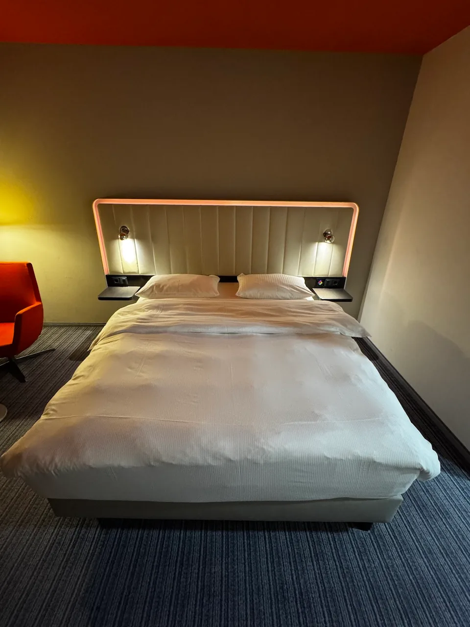 Hotelzimmer mit Doppelbett und Kopfteil in Grautönen