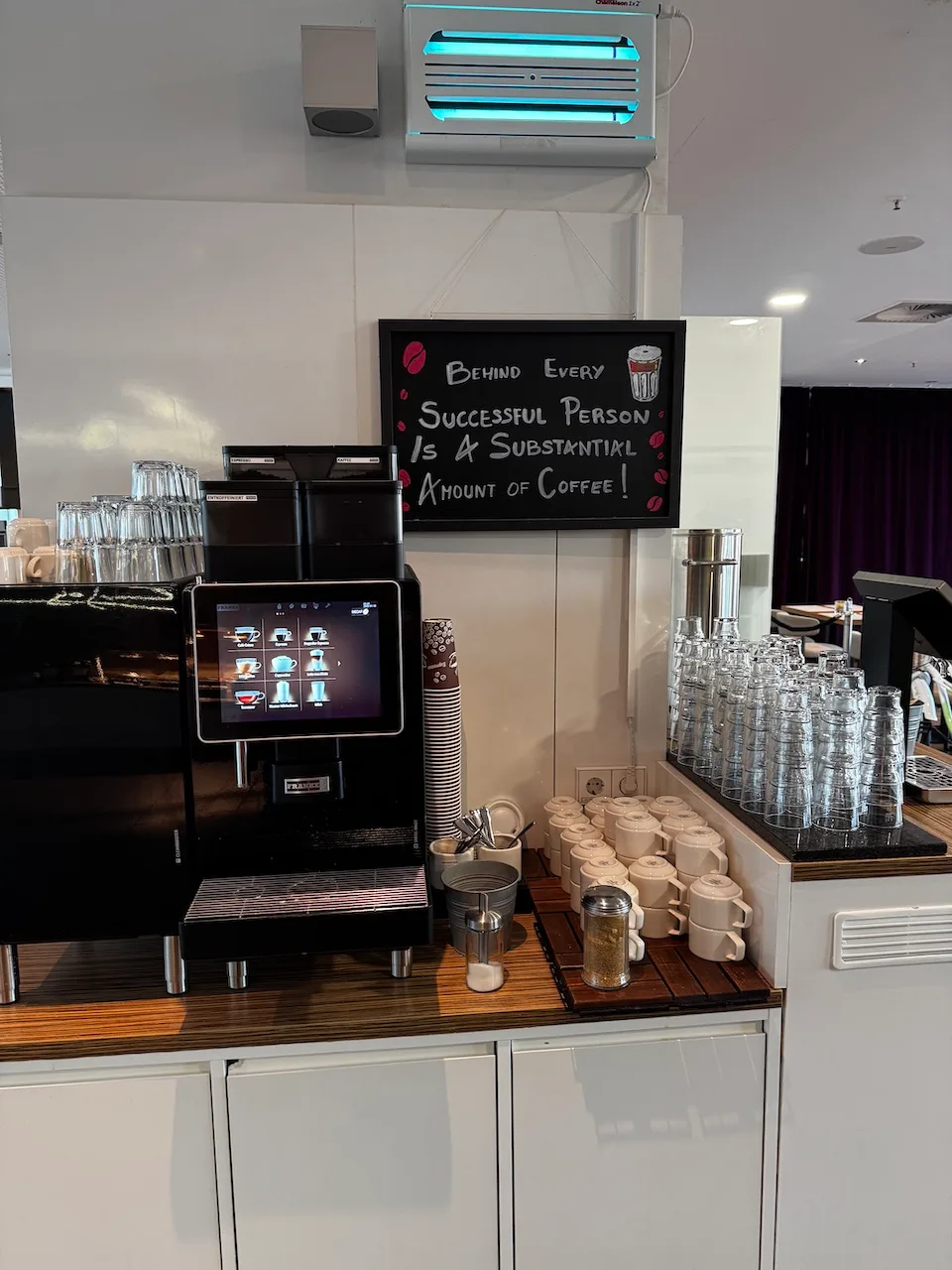 Kaffeeautomat mit Tassen und Kaffeepapieren auf Holztisch