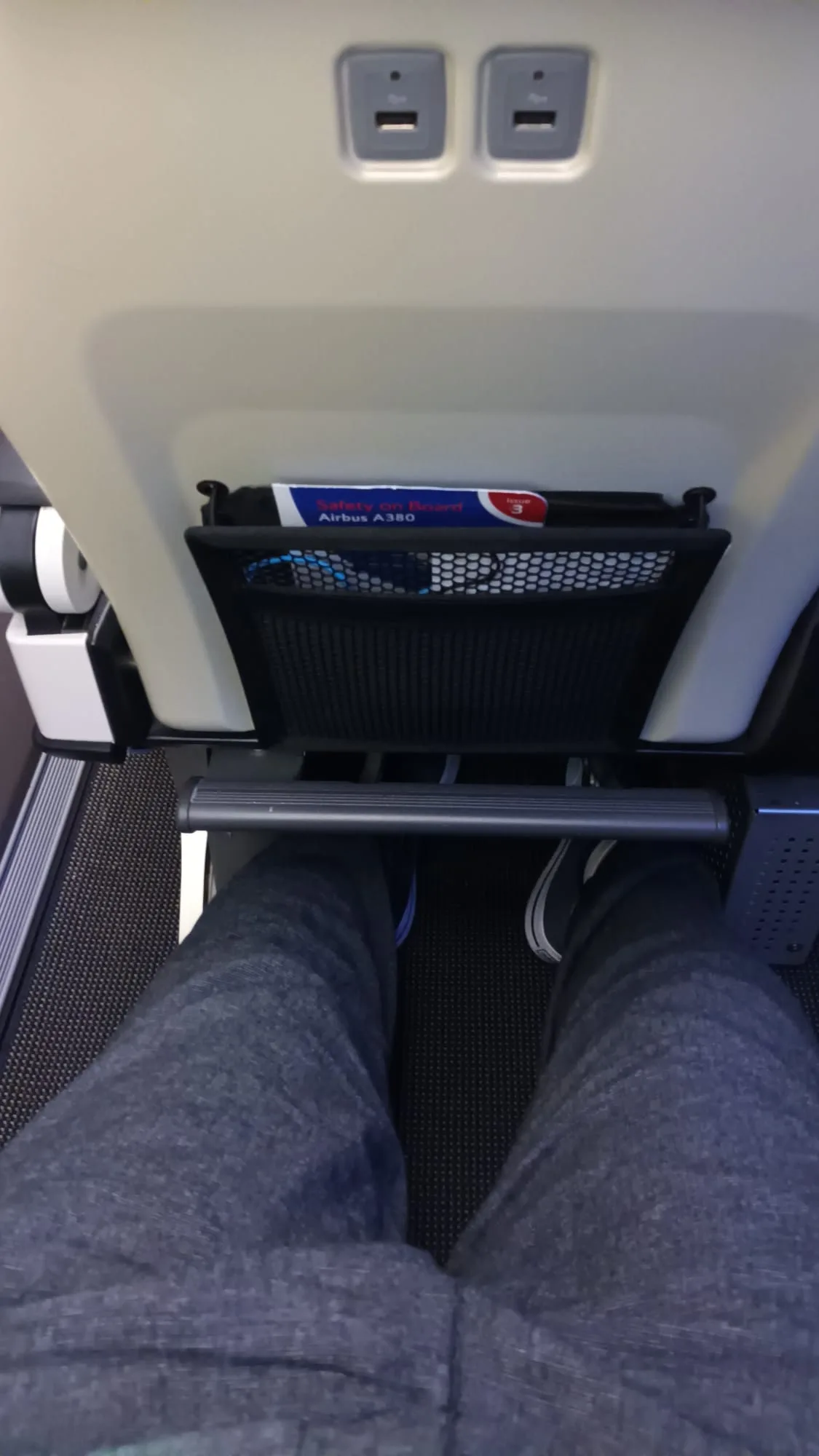 Beine auf dem Boden eines Flugzeugs mit Sitzunterlage und Sicherheitsheft