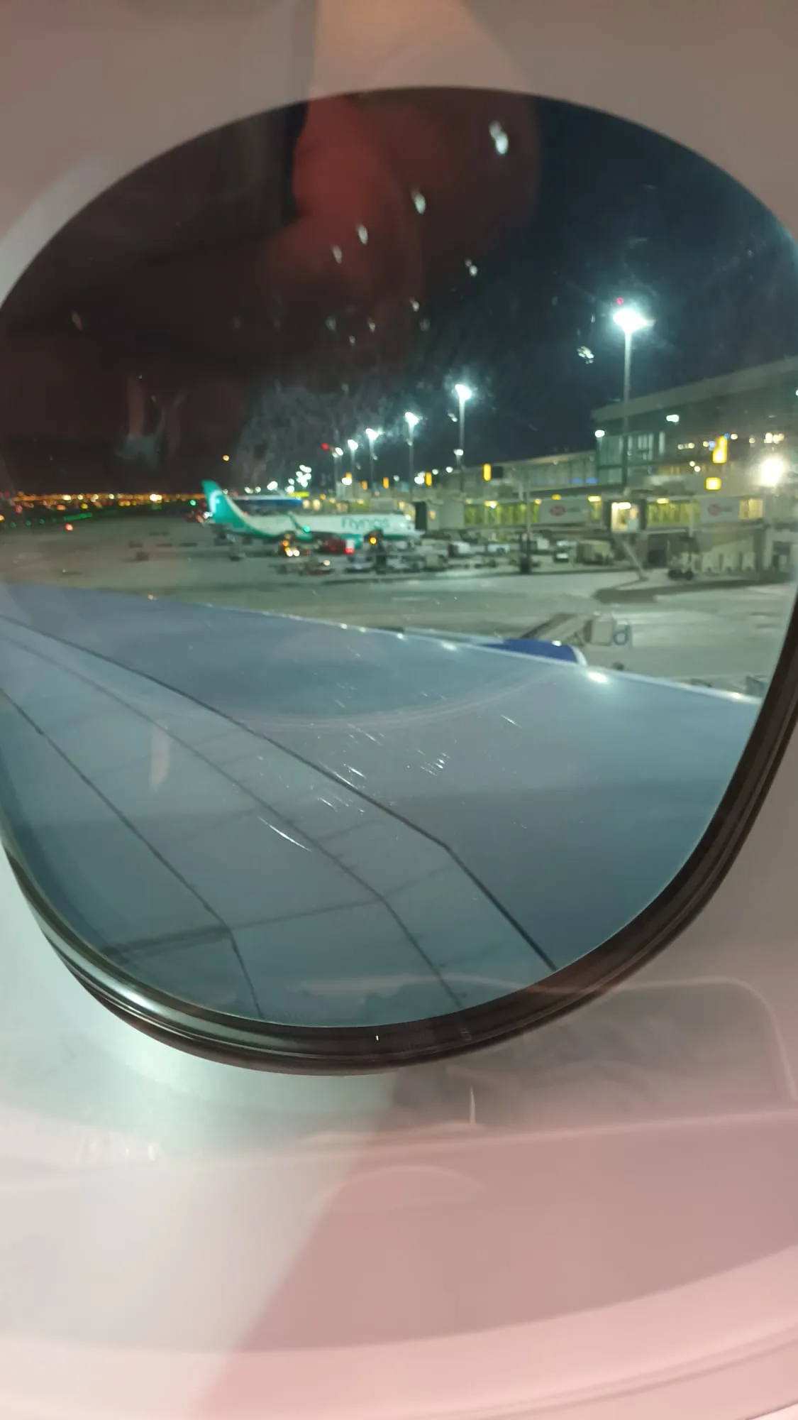 Flugzeugflügel aus Fenster eines Flugzeugs bei Nacht