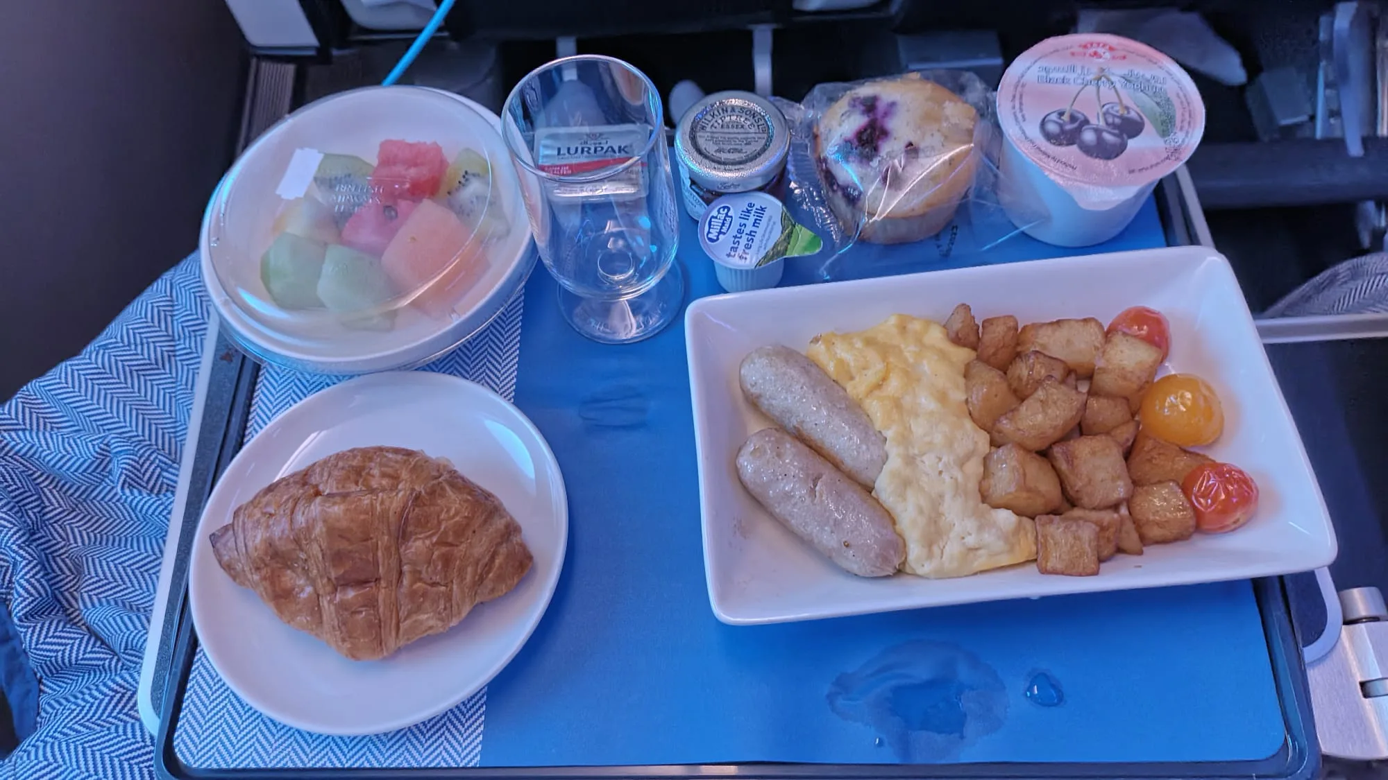 Frühstückstablett mit Croissant, Eiern, Würstchen und Früchten
