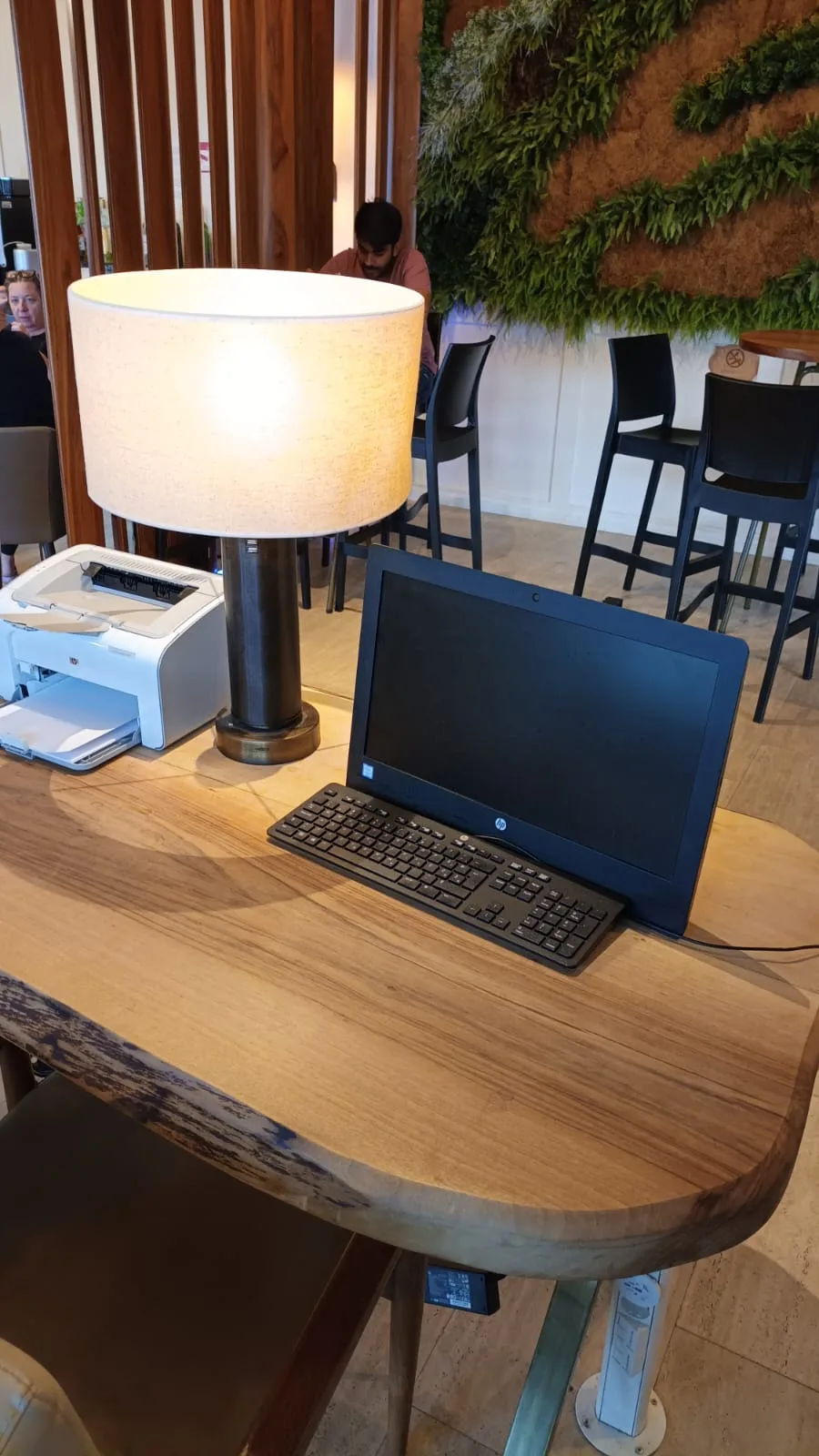 Holztisch mit Laptop, Tastatur und Lampe im Loungesetting