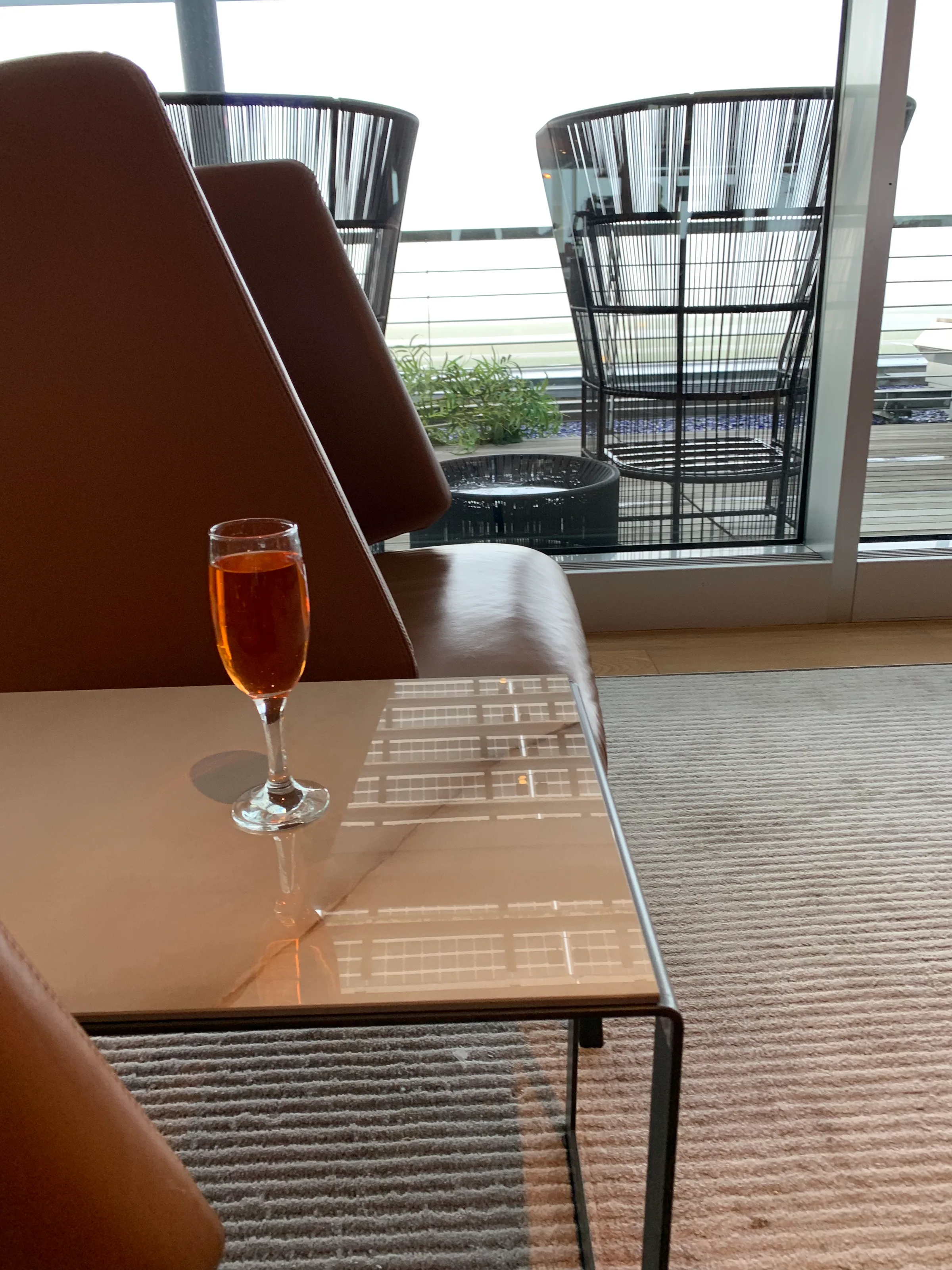 Glas mit orangefarbener Flüssigkeit auf niedrigem Tisch im Loungesessel