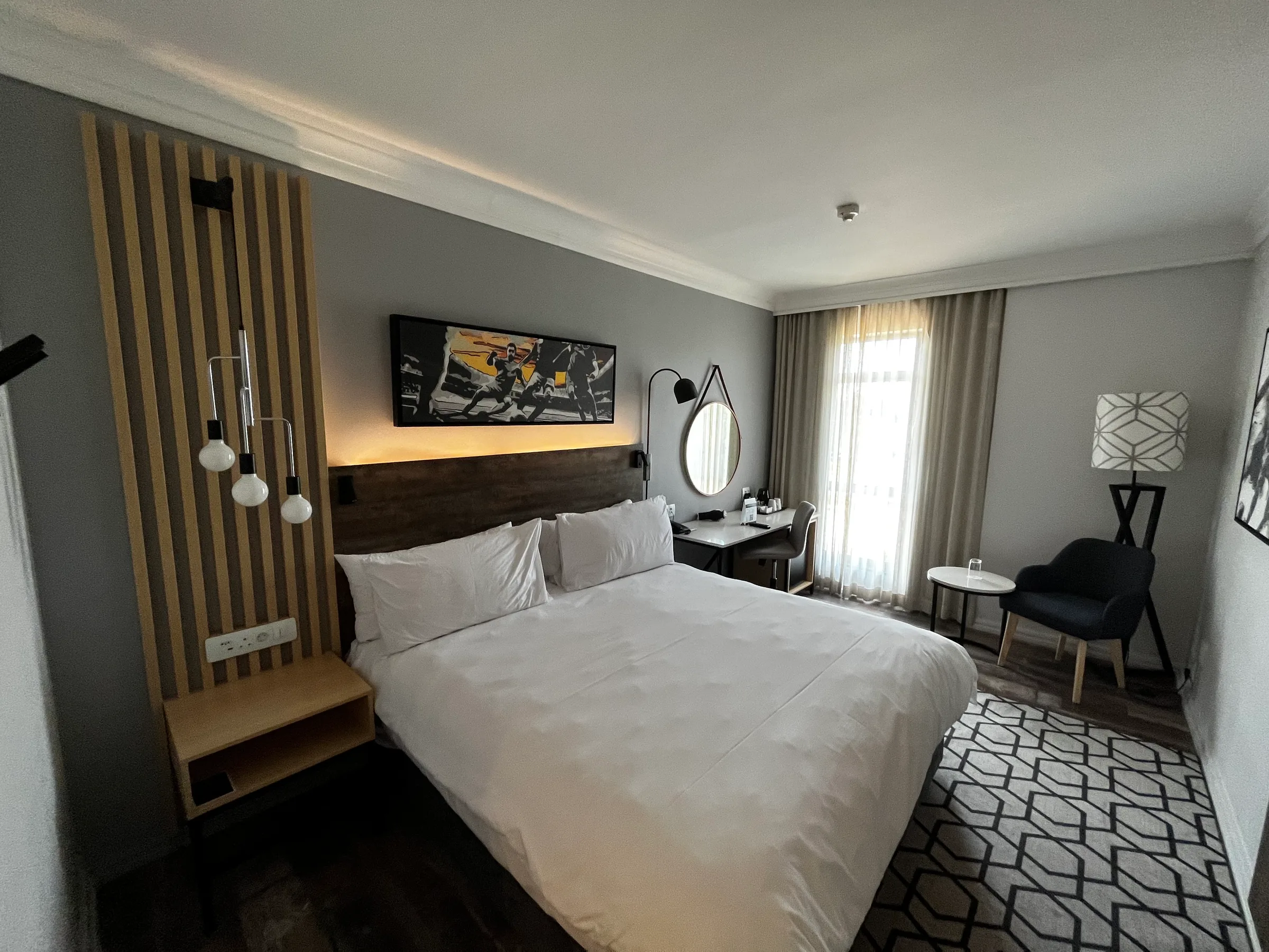 Hotelzimmer mit Doppelbett und Holzverkleidung an der Wand