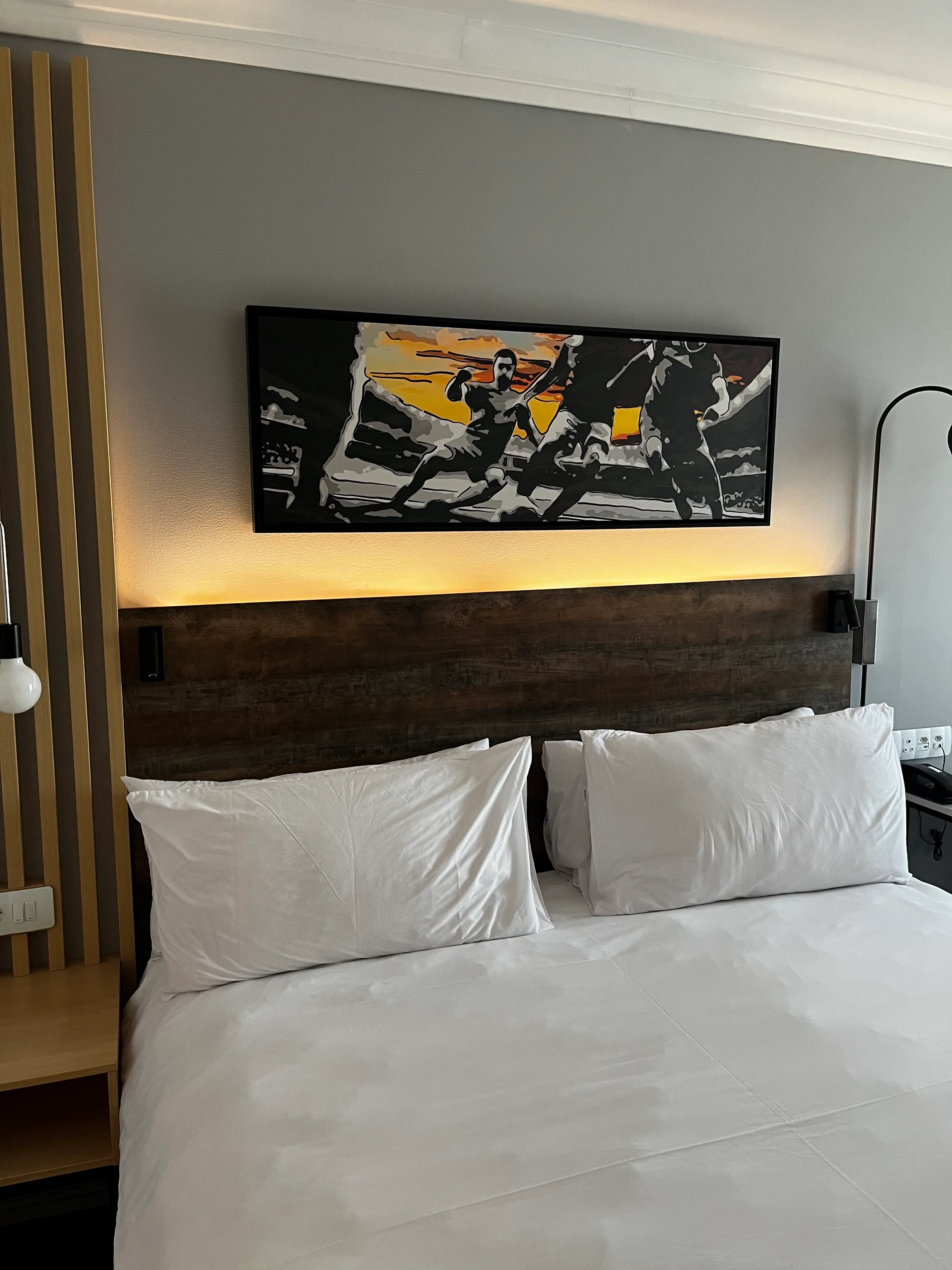 Doppelbett im Hotelzimmer mit Holzbettgestell und Wandbild