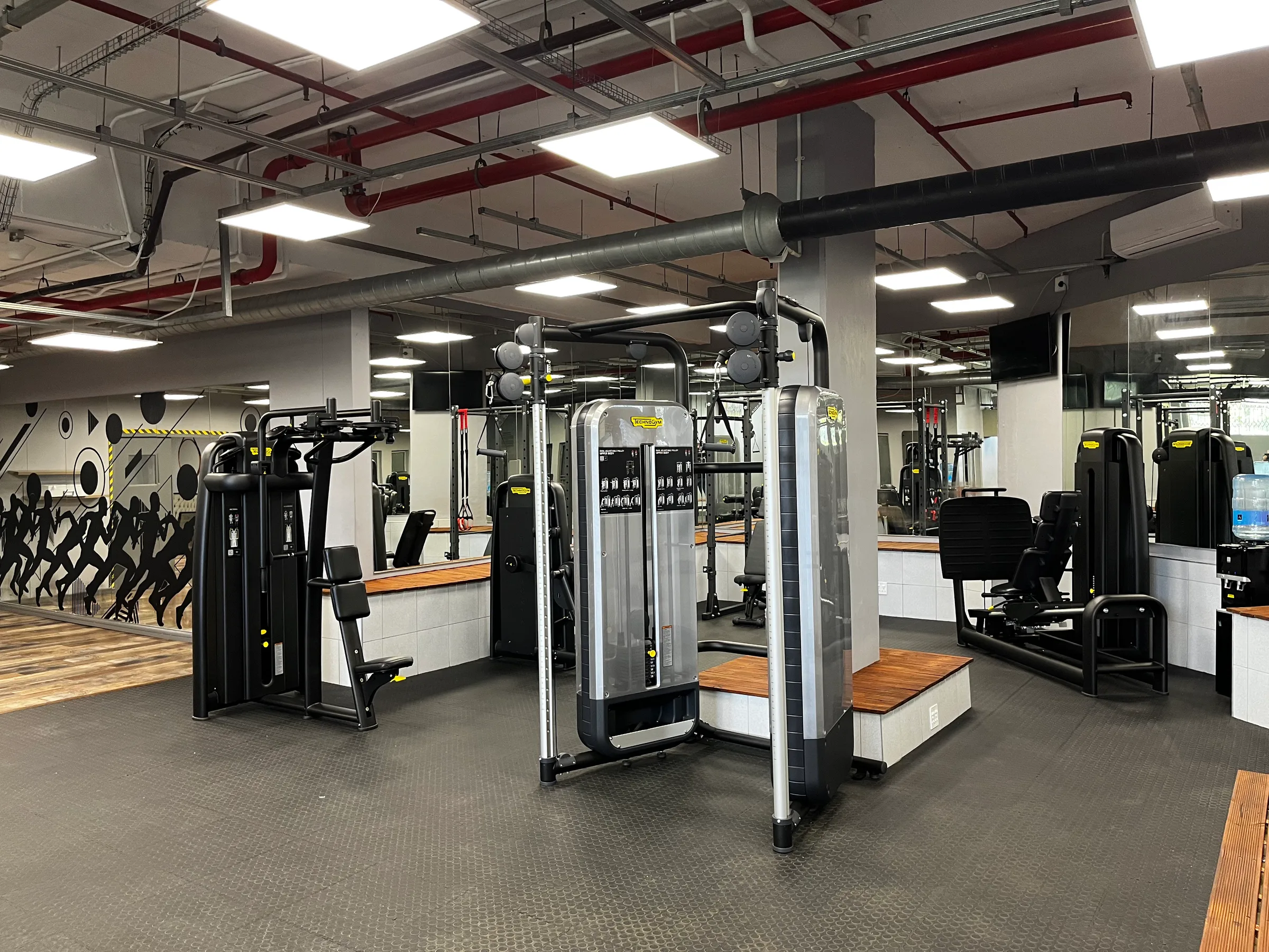 Fitnessraum mit verschiedenen Trainingsgeräten und Spiegeln