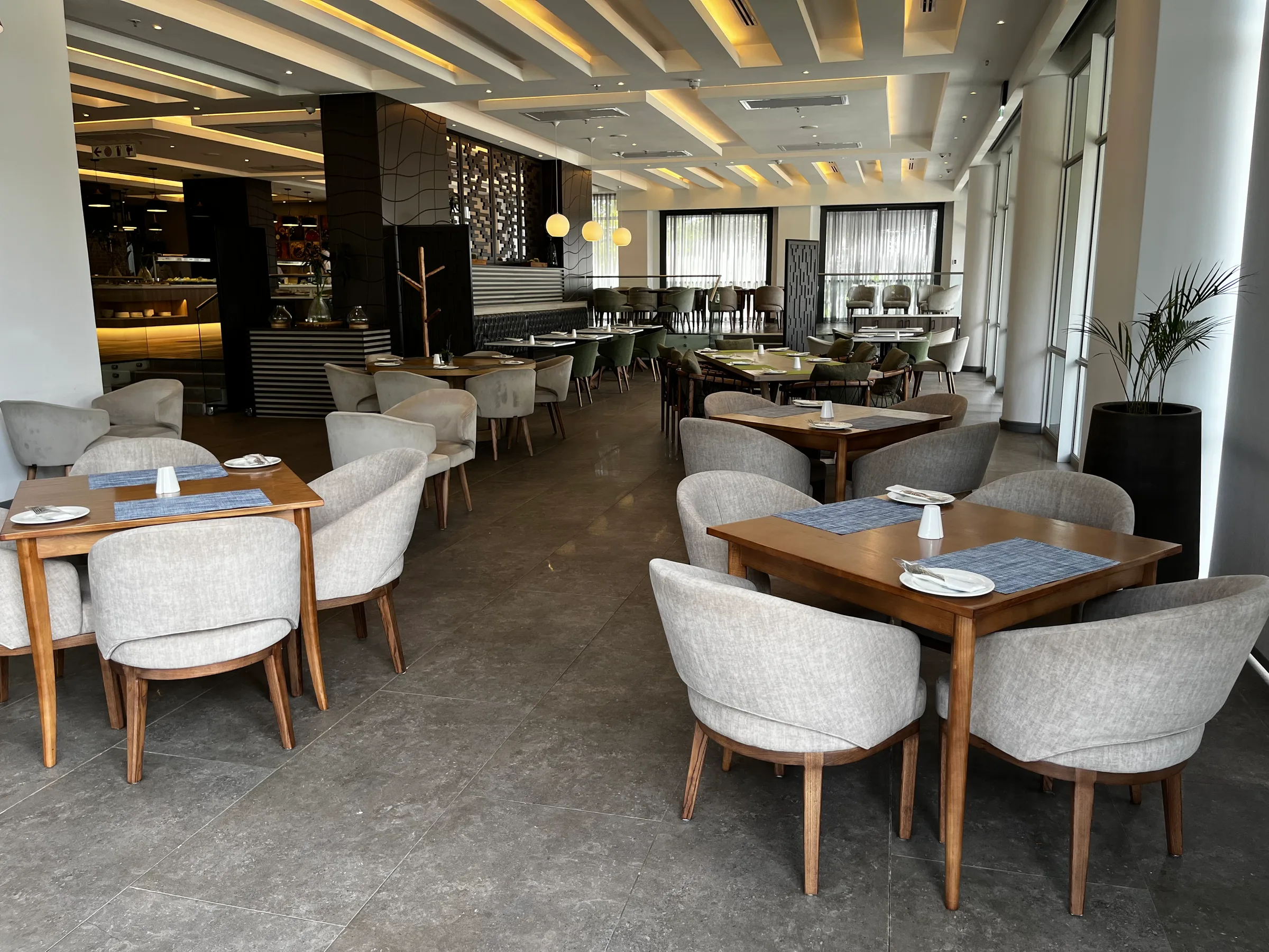 Essbereich im Hotel mit Holztischen und grauen Stühlen
