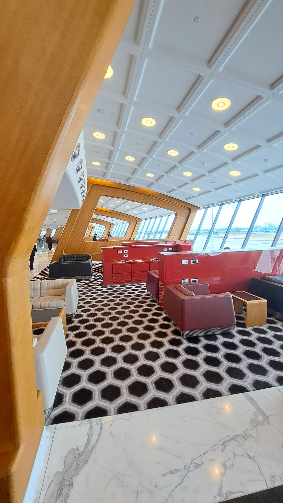 Lounge mit roten Sesseln und geometrischem Teppich