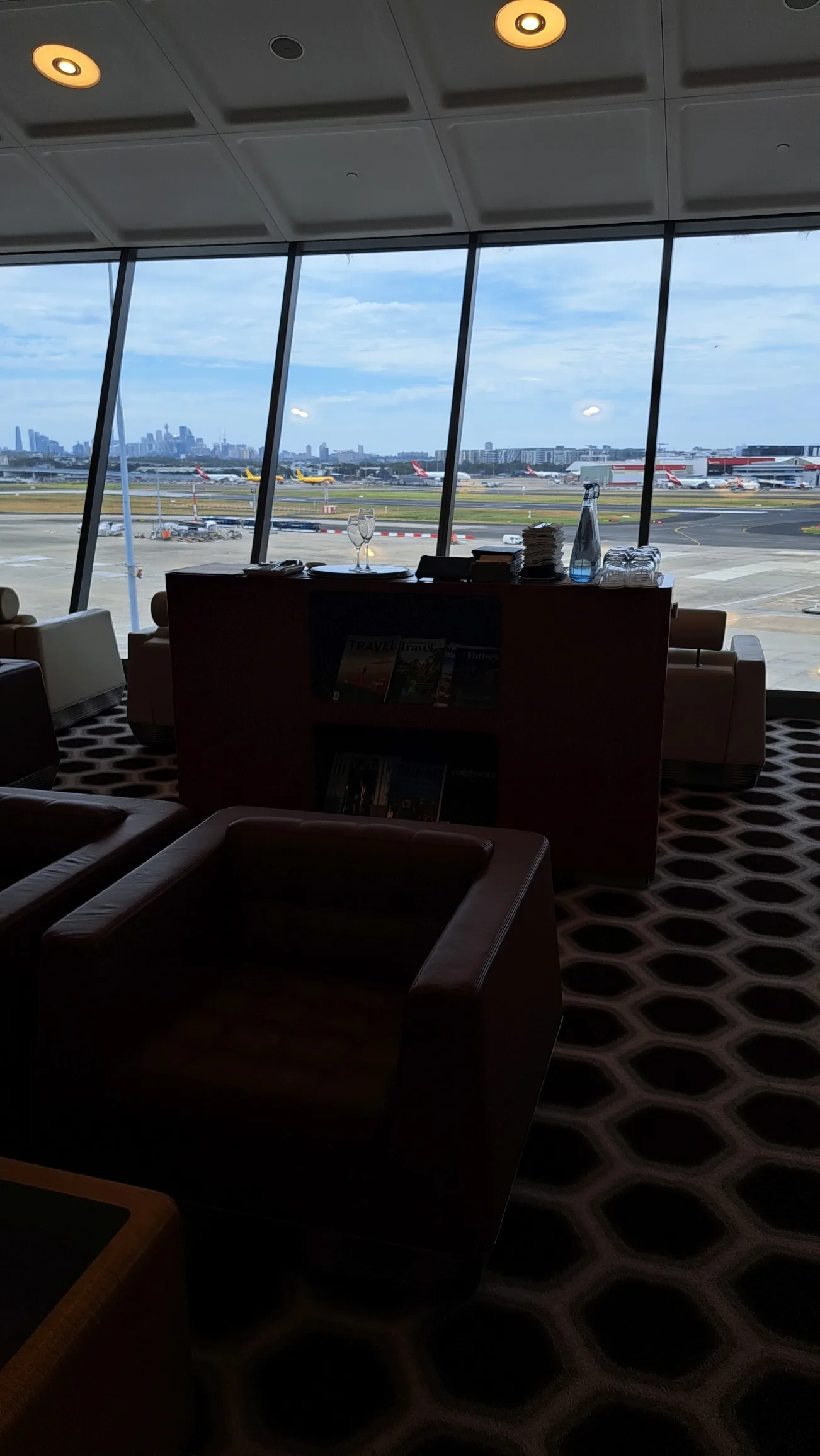 Qantas First Lounge mit Sitzgelegenheiten und Blick auf Flugzeuge am Flughafen