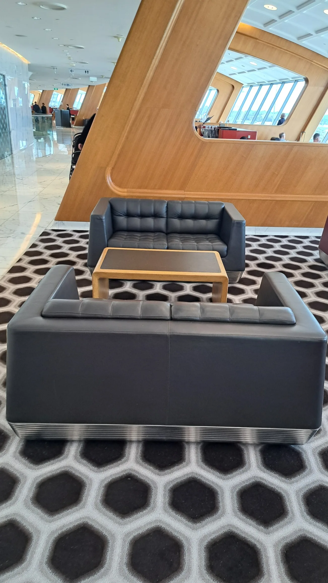Sofa im Qantas First Lounge mit Holztisch und Musterboden