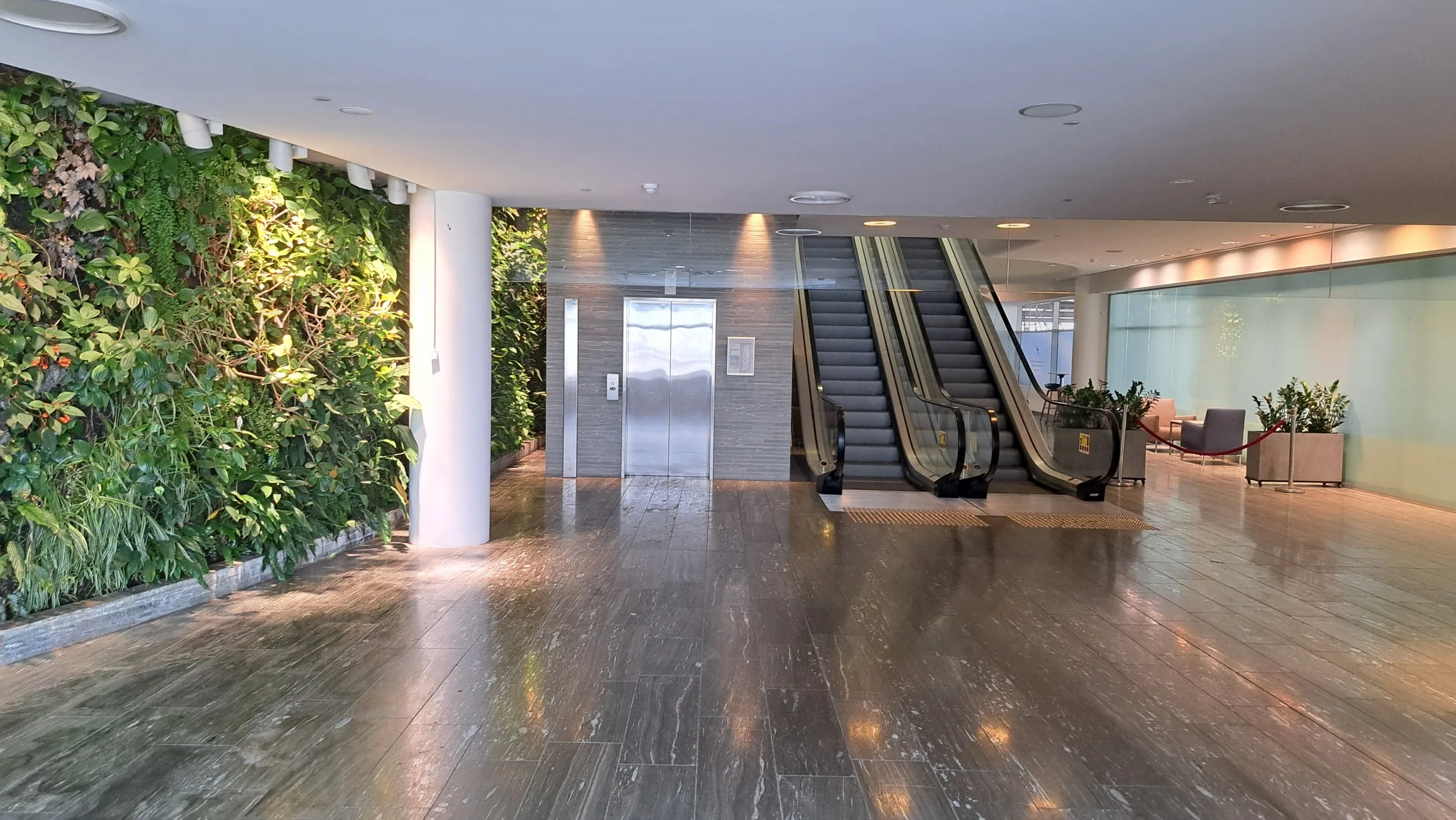 Lobby mit Rolltreppe und Pflanzenwand