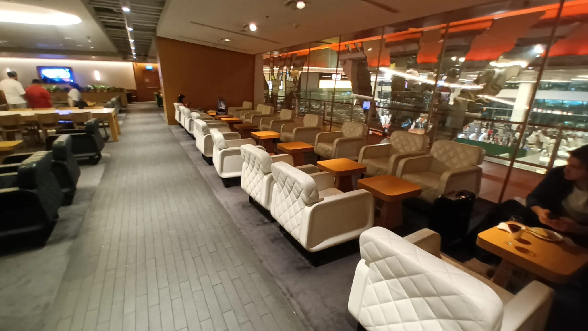 Lounge mit weißen Sesseln und Holztischen