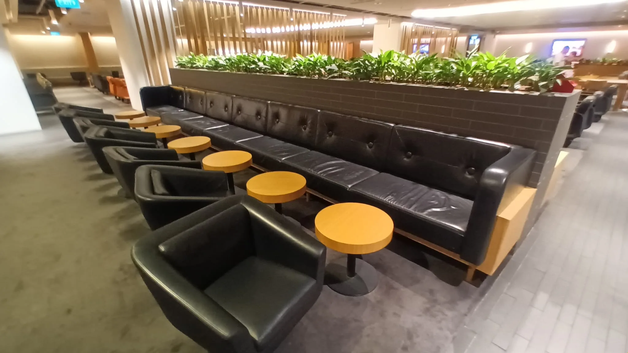 Lounge mit schwarzen Ledersofas und Holztischen