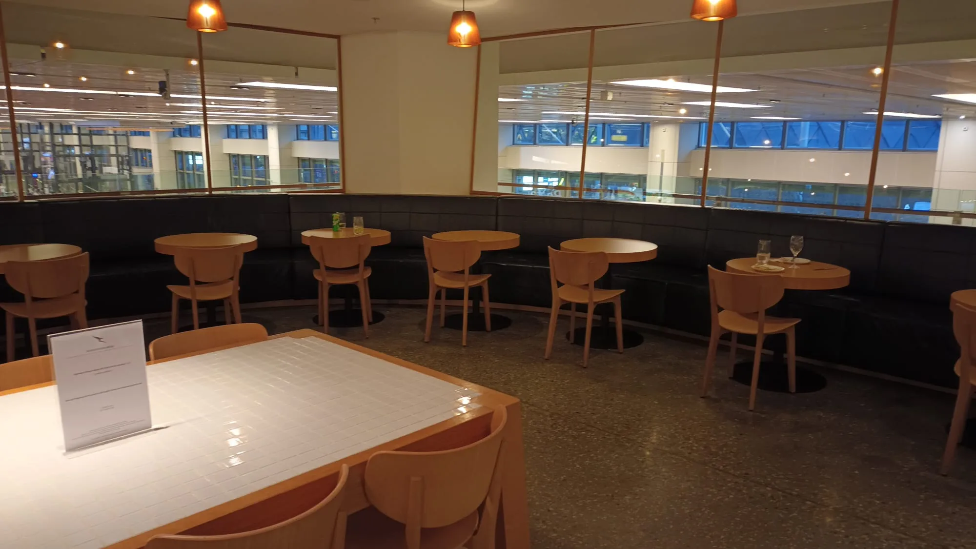 Lounge mit Holztischen und Stühlen, Sitzbank im Hintergrund