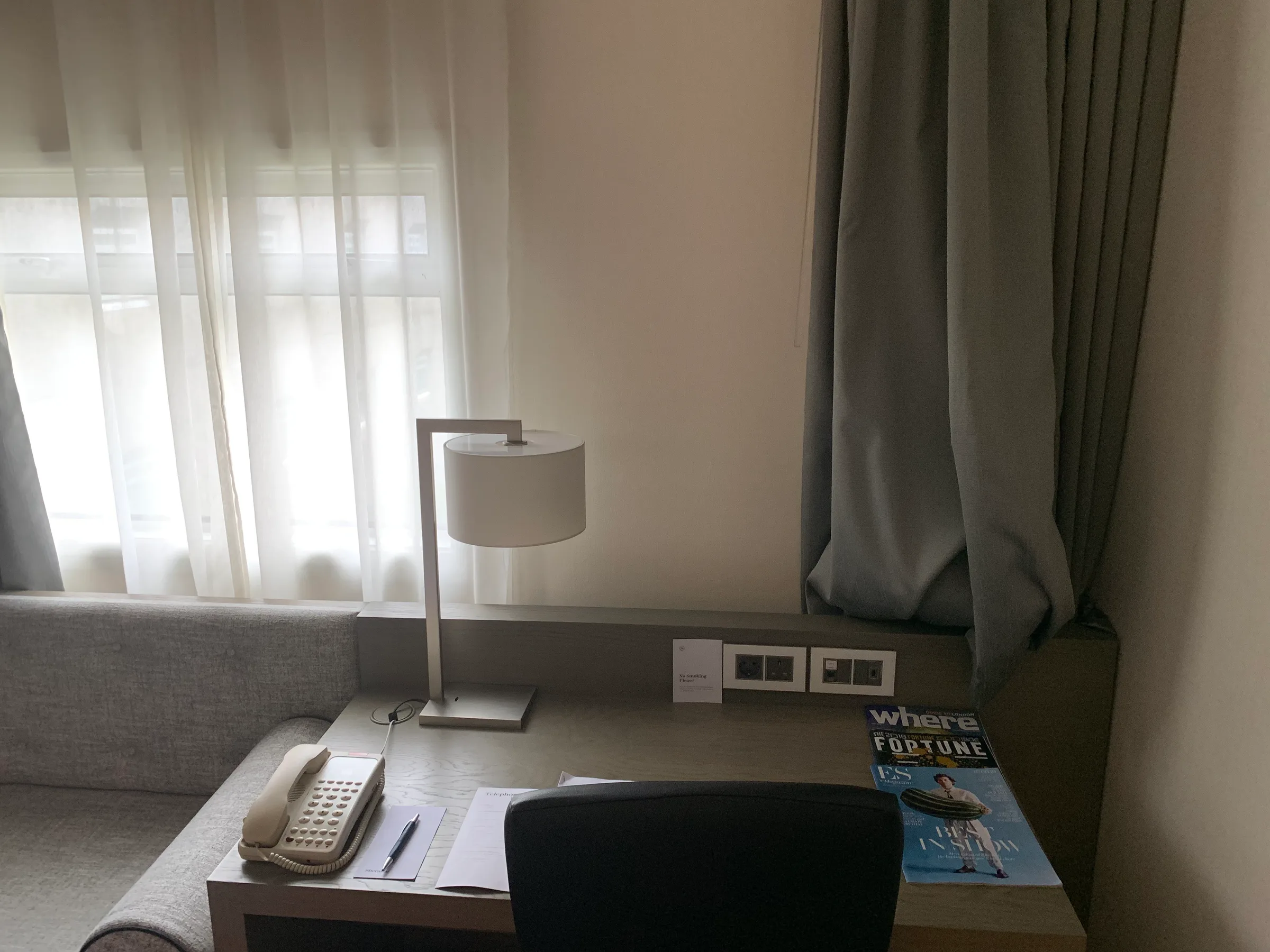 Hotelzimmer mit Schreibtisch, Lampe und Zeitungen