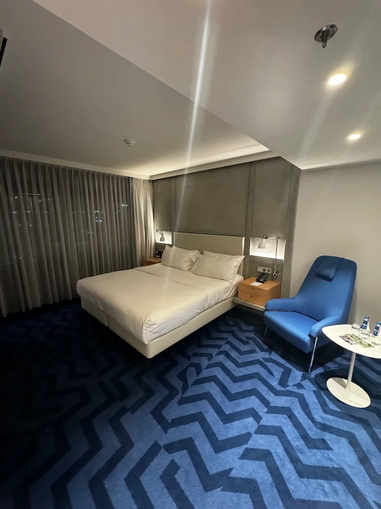 Hotelzimmer mit Doppelbett und blauem Sessel