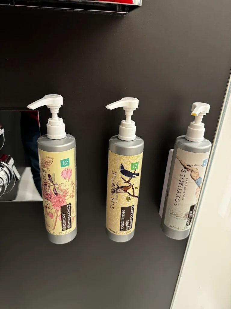 Drei Flaschen Shampoo, Conditioner und Haarspray von Tokyomilk auf einem Regal