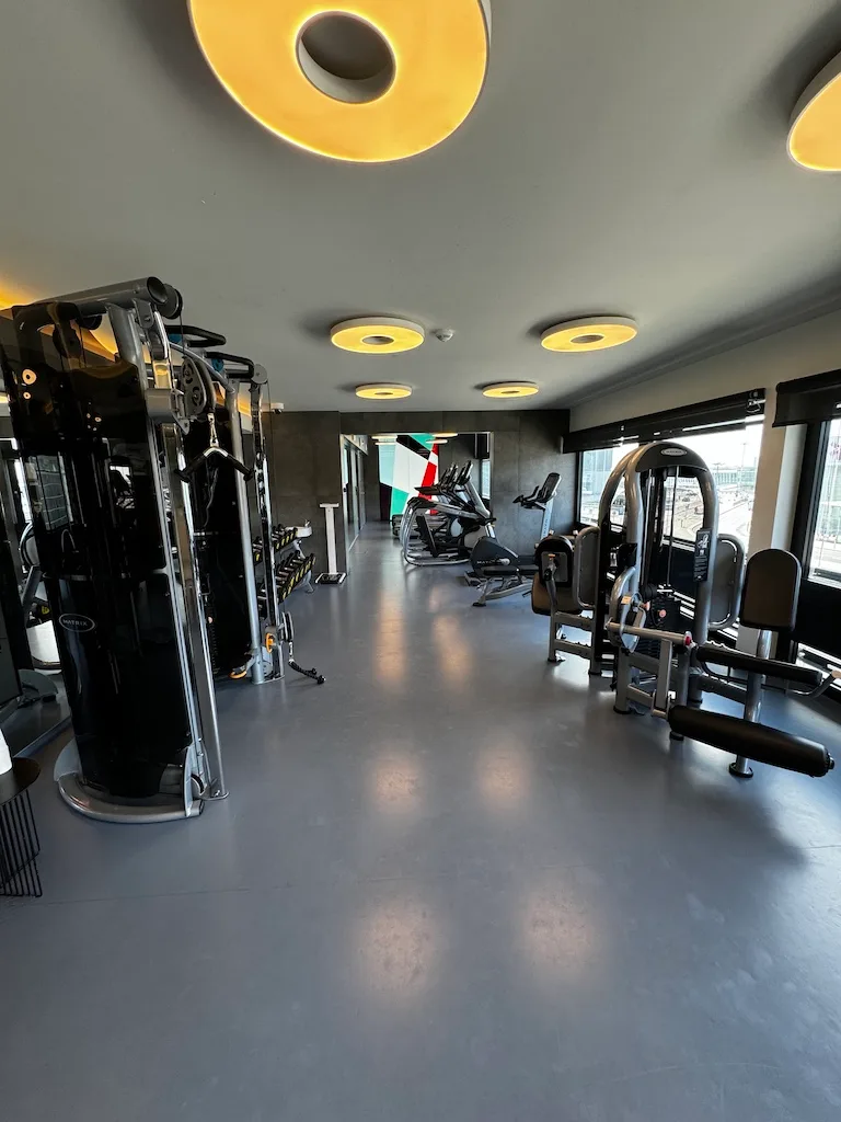 Fitnessraum mit verschiedenen Trainingsgeräten und Spiegeln