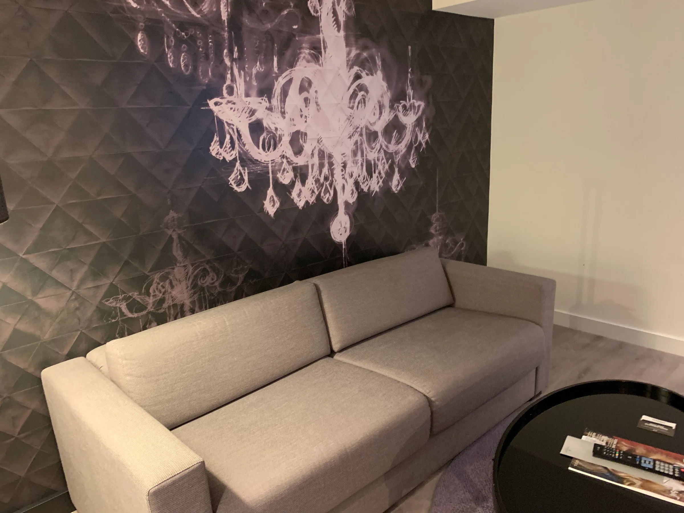 Graues Sofa vor Wand mit abstraktem Kronleuchter-Motiv