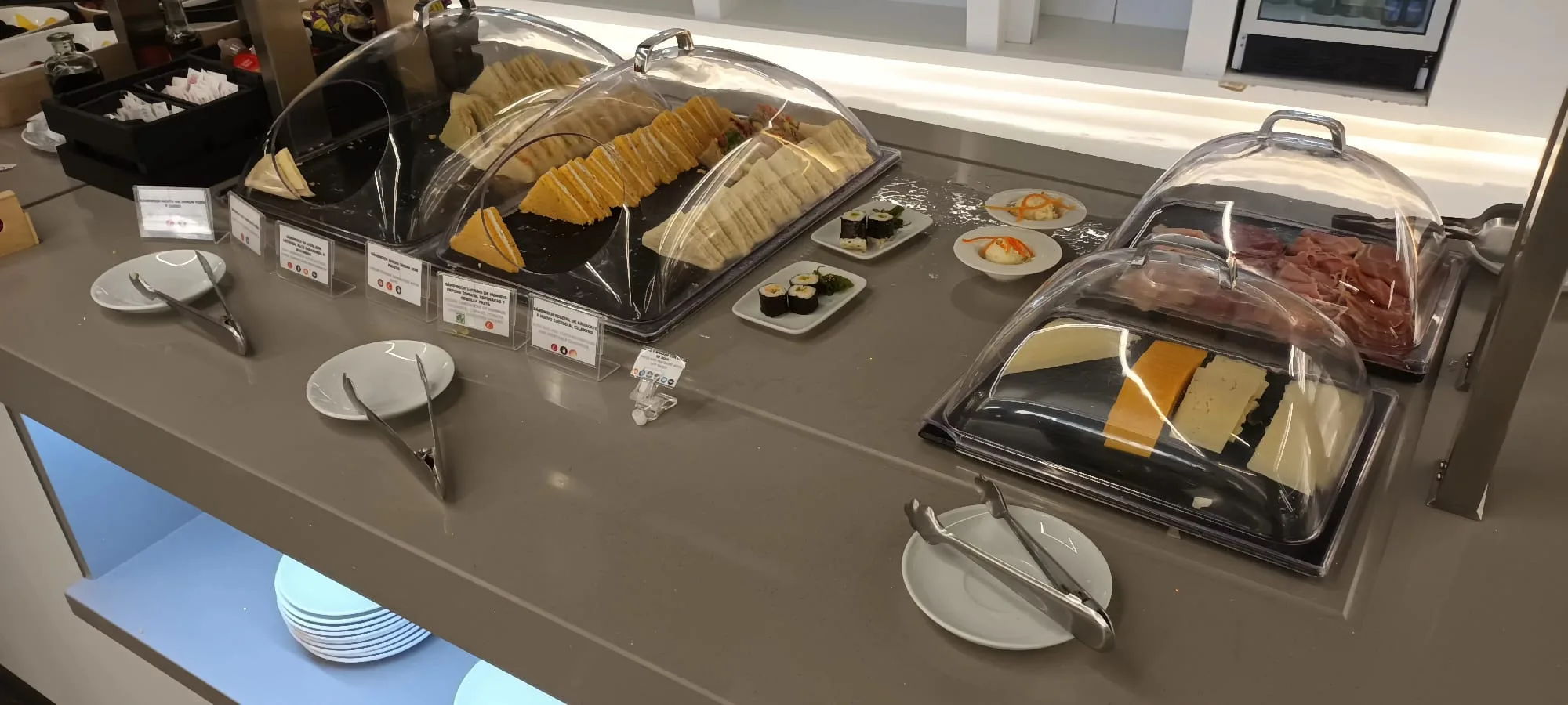 Buffet mit Sandwiches, Käse und Fleisch unter Schutzkuppeln