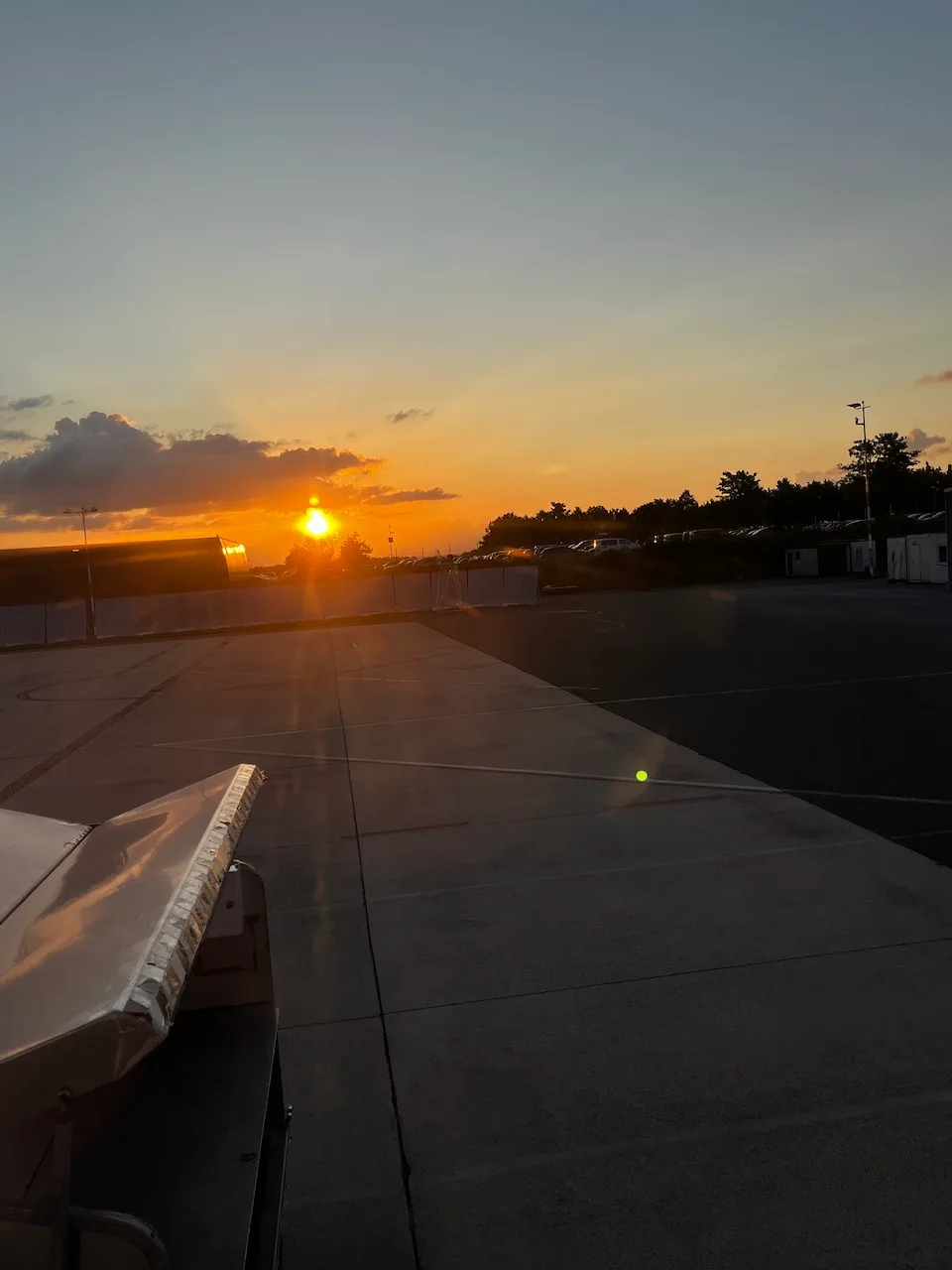 Flughafen-Parkplatz bei Sonnenuntergang mit Flugzeugflügel