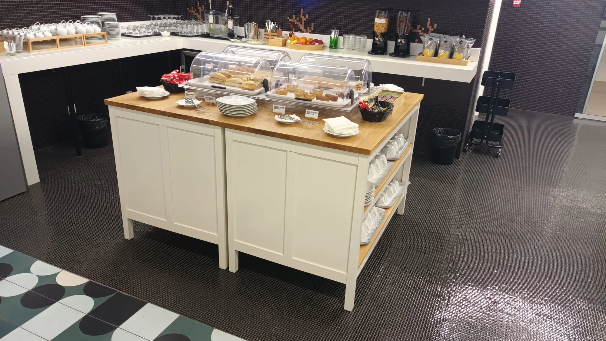 Buffet mit Gebäck und Getränken auf Holztisch im Flughafenlounge
