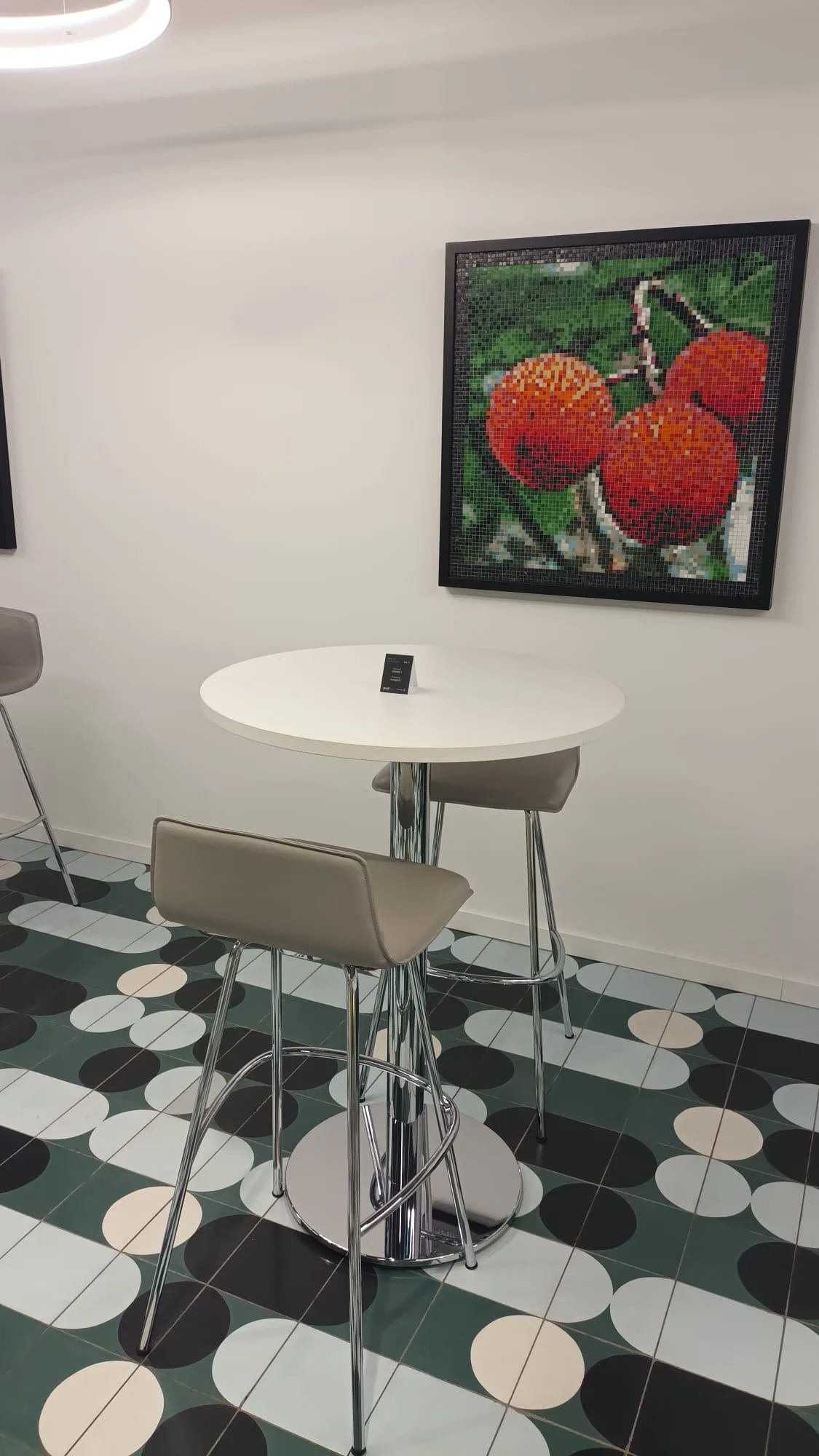 Kleiner Loungetisch mit Stühlen und Obstmosaik an der Wand