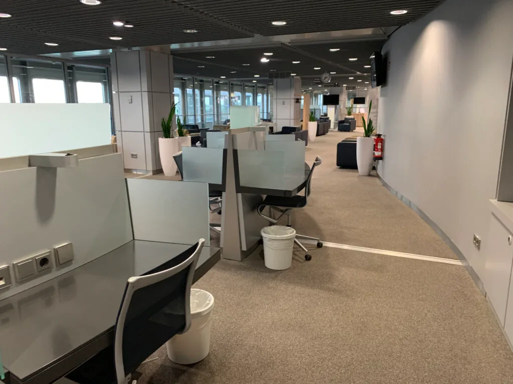 Leere Flughafenlounge mit Arbeitsplätzen und Sicht auf andere Bereiche