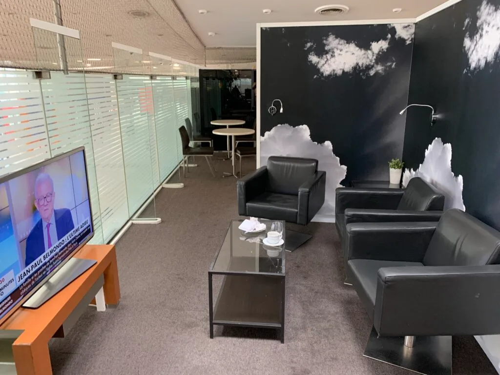 Lounge mit Sesseln und Fernseher im Flughafen