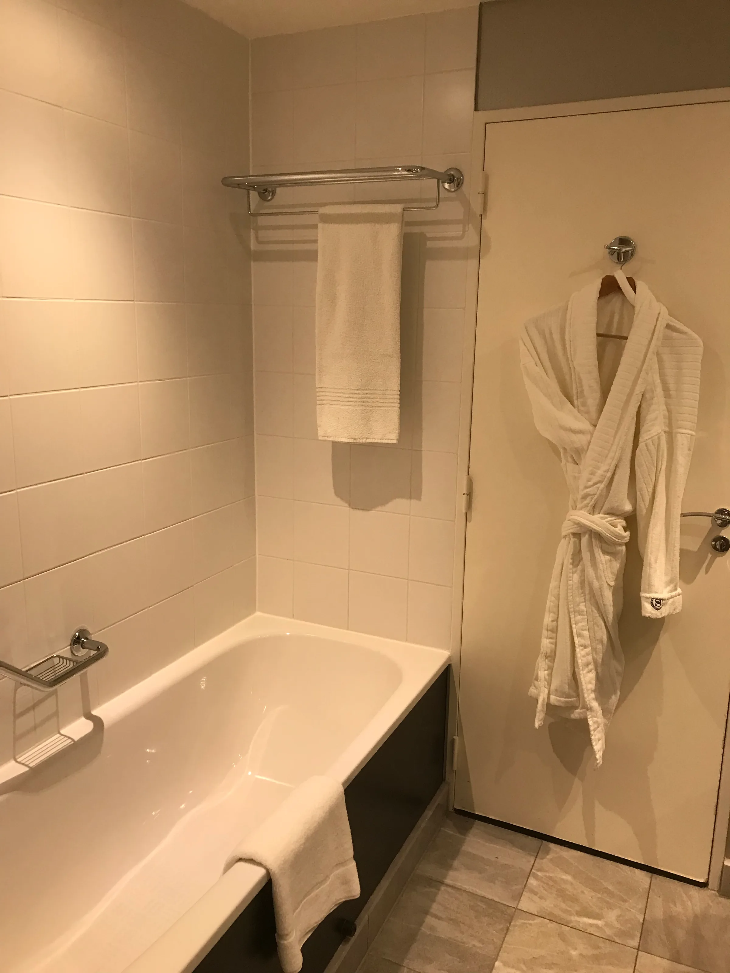 Hotelbad mit Badewanne, Handtuchhalter und Bademantel