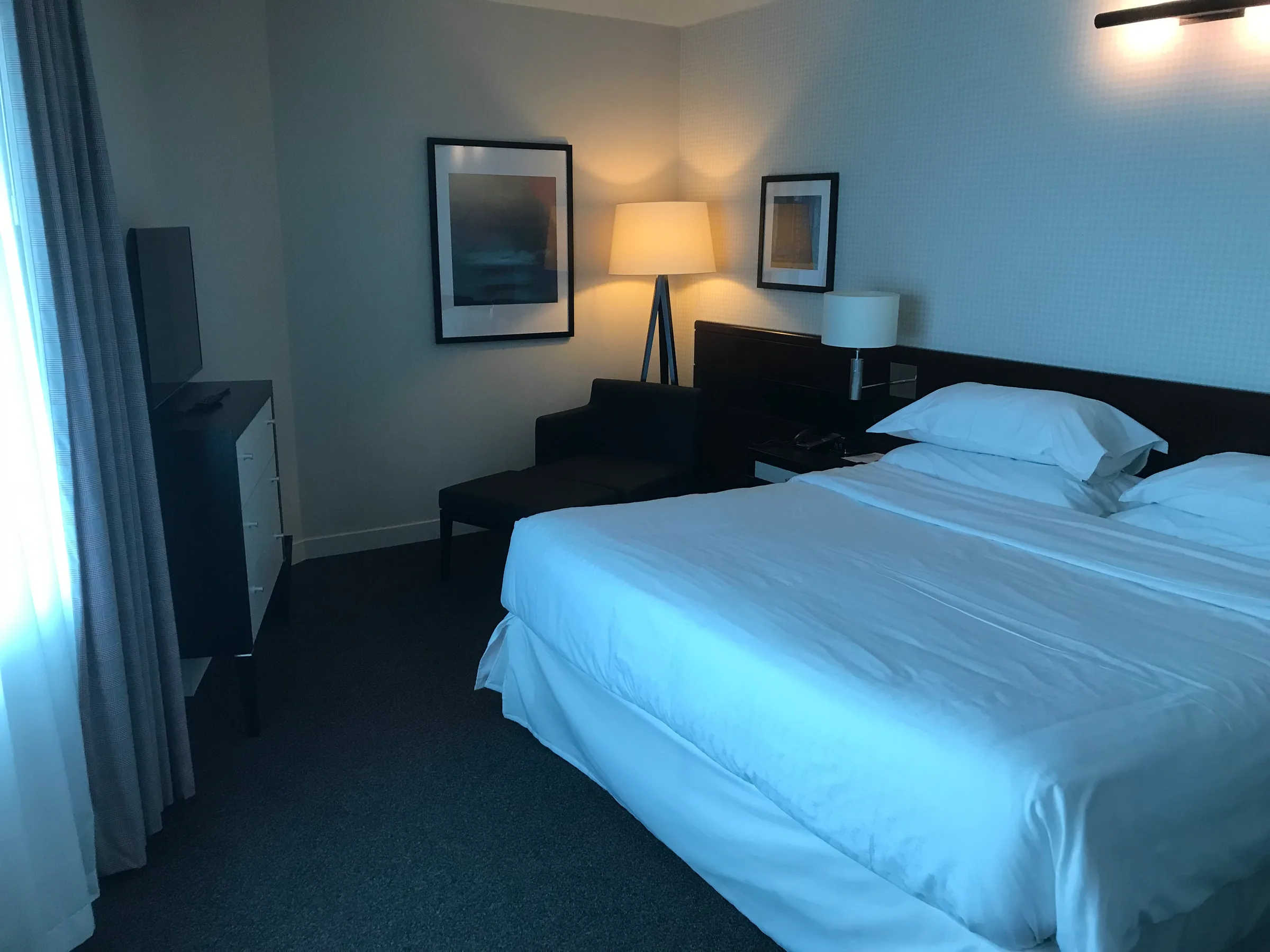 Hotelzimmer mit Doppelbett und Nachttischen in neutralen Farben