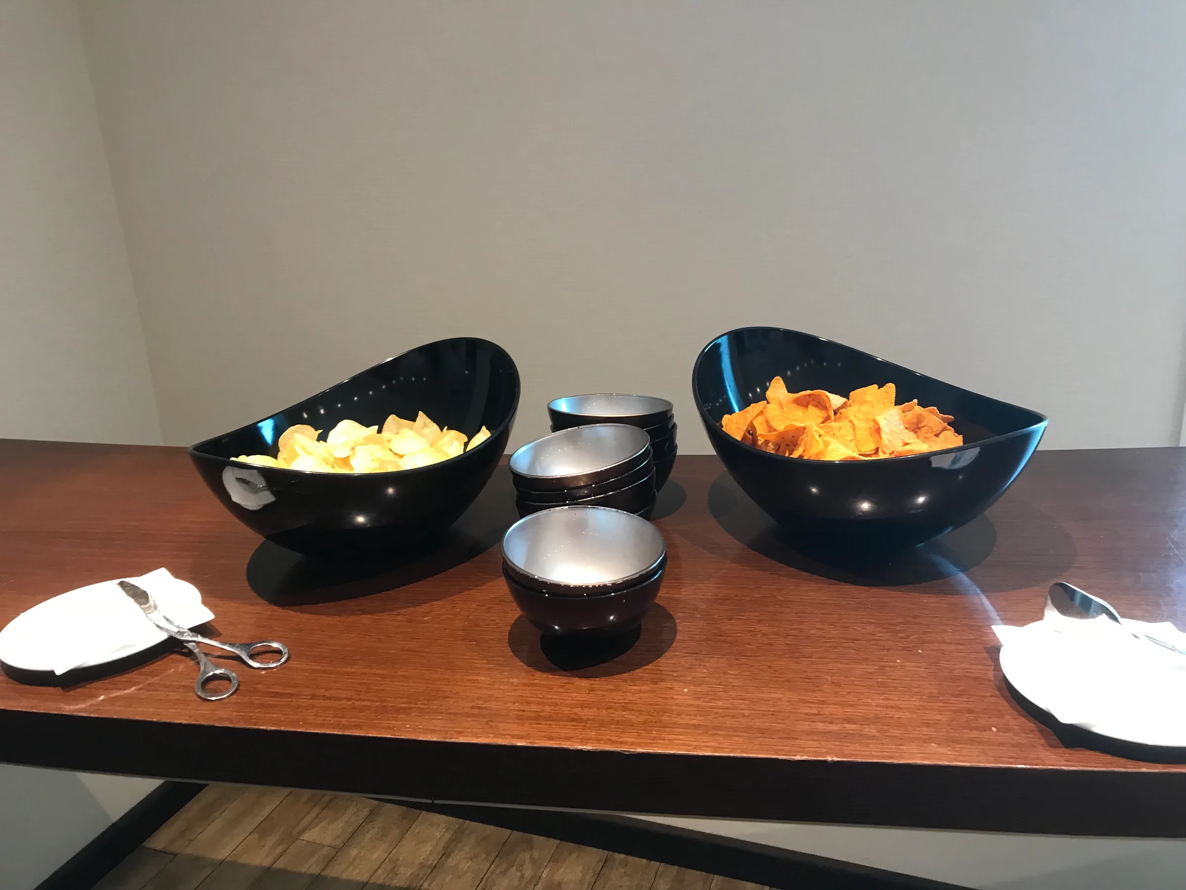 Schwarze Schüsseln mit Chips auf Holztisch