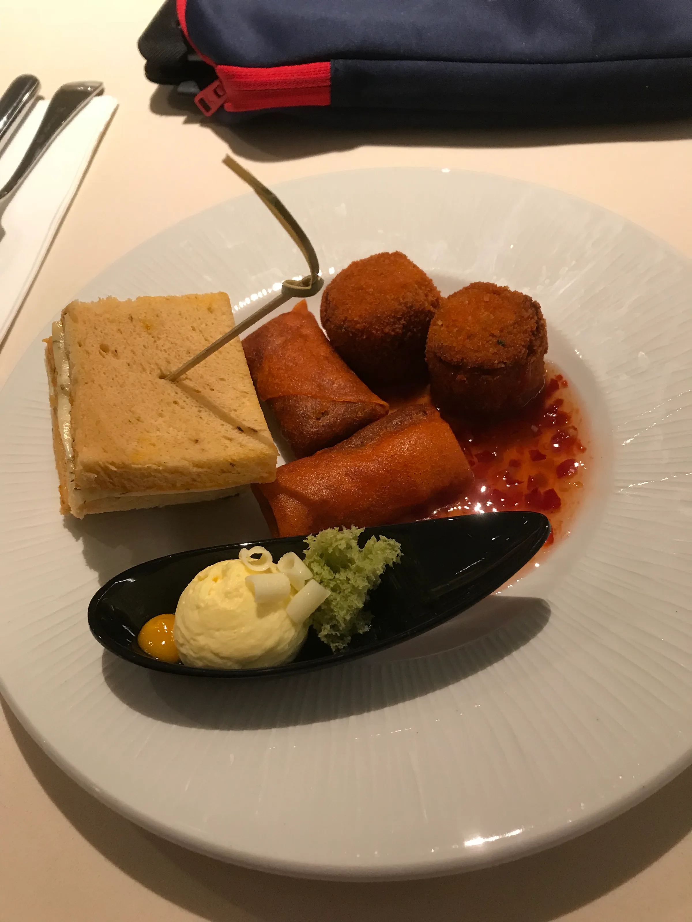 Snackplatte mit Sandwich, Springrollen und Eiscreme auf weißem Teller
