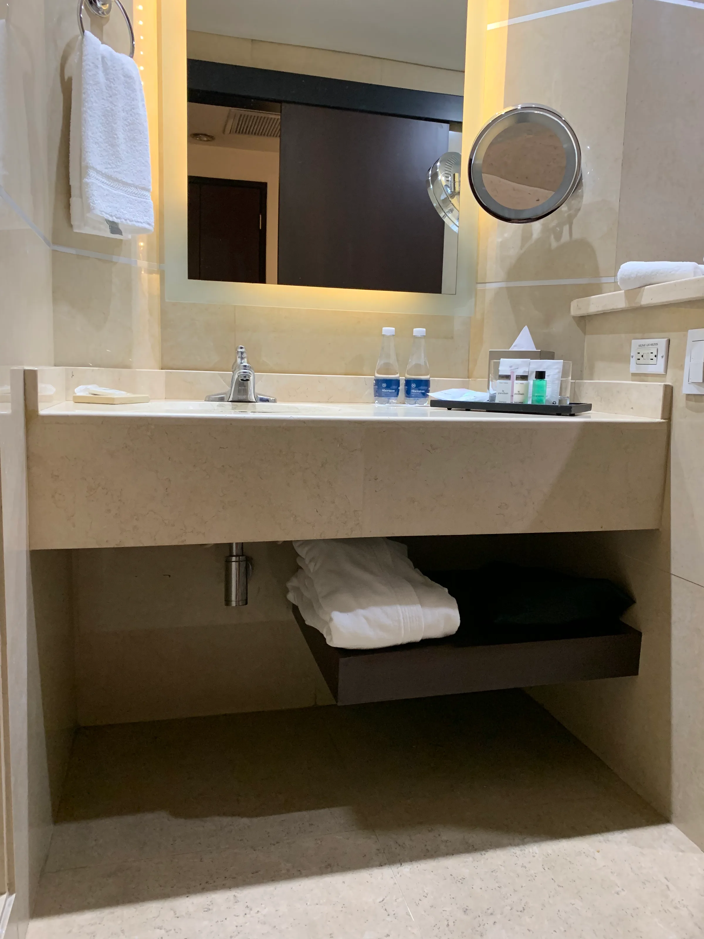 Hotelwaschtisch mit Spiegel und Flaschen auf dem Regal