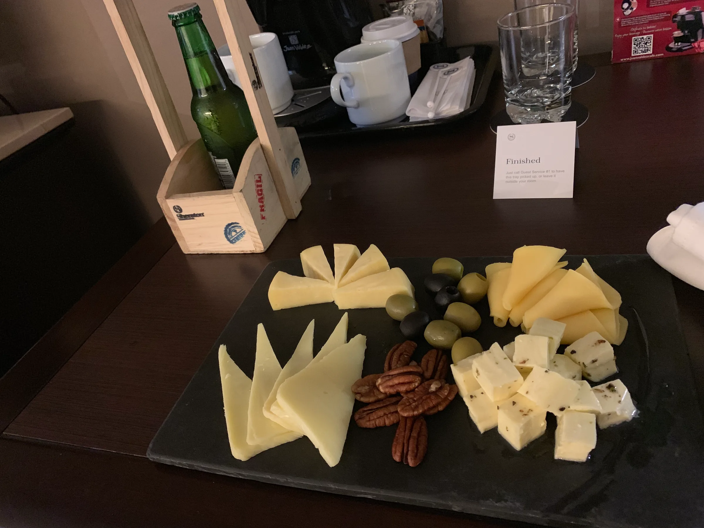 Käseplatte mit verschiedenen Käsesorten, Oliven und Nüssen auf Tisch im Hotelzimmer