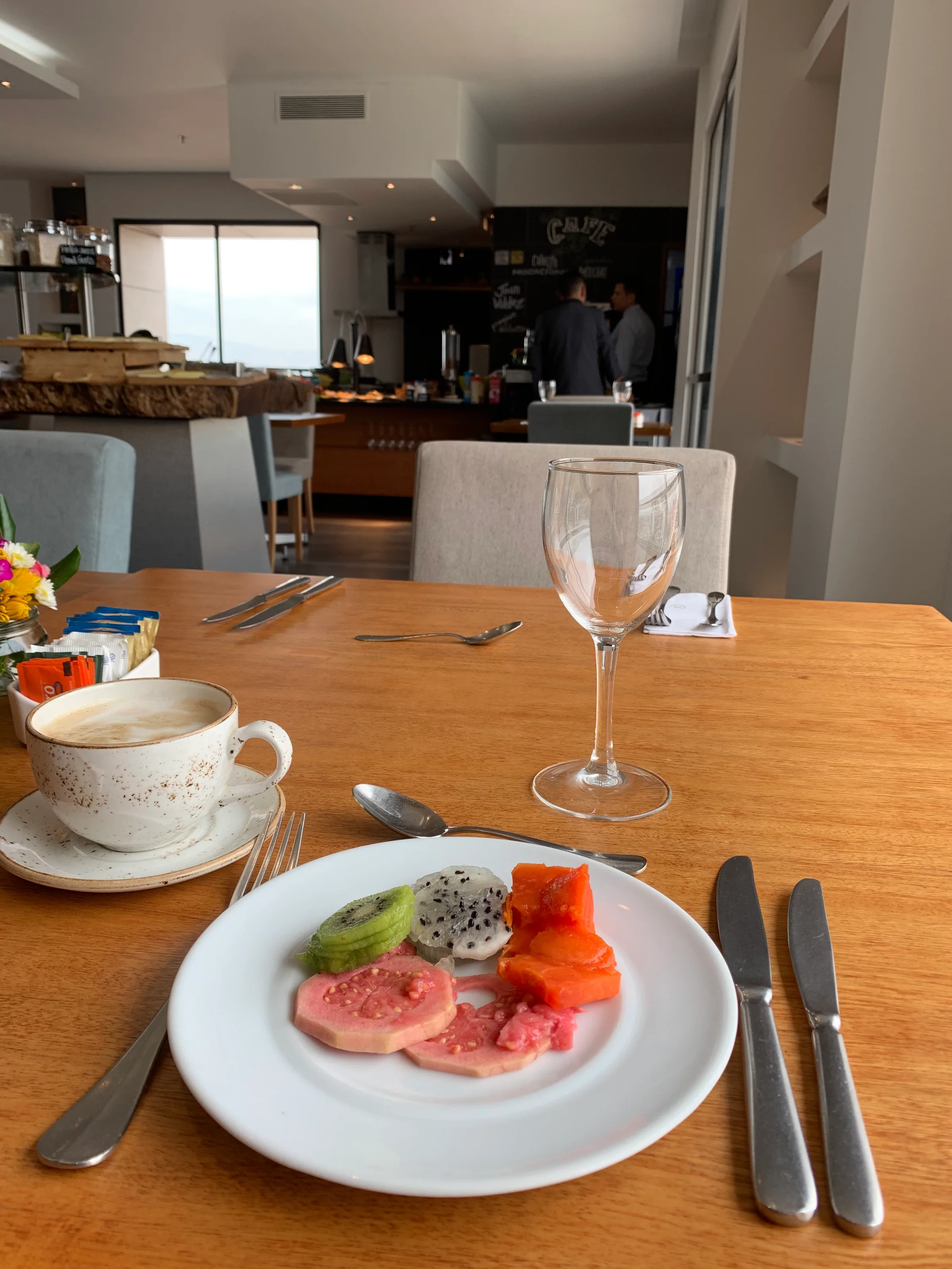 Frühstücksteller mit Obst und Kaffee auf Holztisch im Hotelrestaurant
