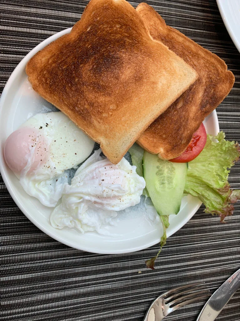 Gekochte Eier mit Toast und Salat auf Teller