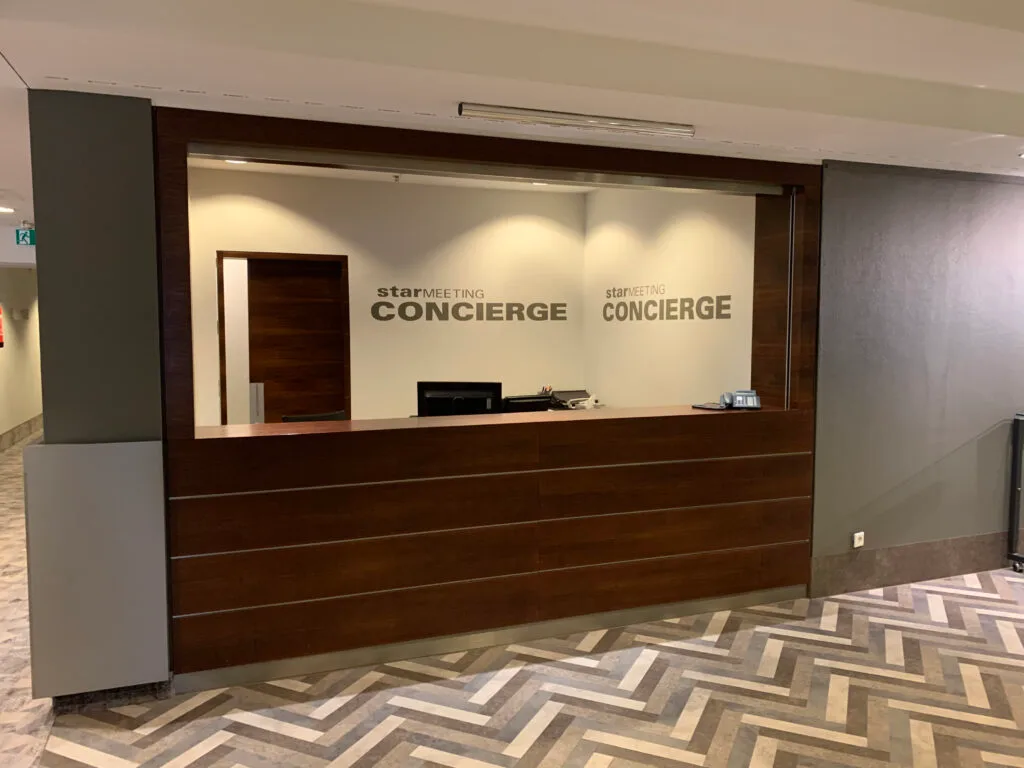 Rezeption mit Schildern 'starMEETING CONCIERGE' an der Wand